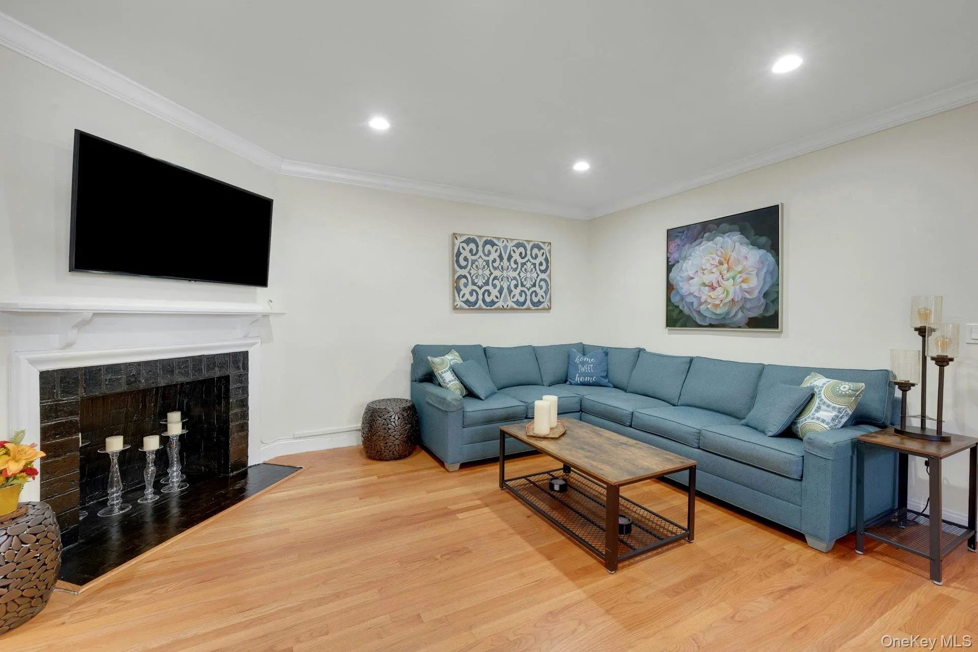 Living room featuring crown molding, wood finished floors, recessed lighting, and a fireplace Living room featuring crown molding, wood finished floors, recessed lighting, and a fireplace