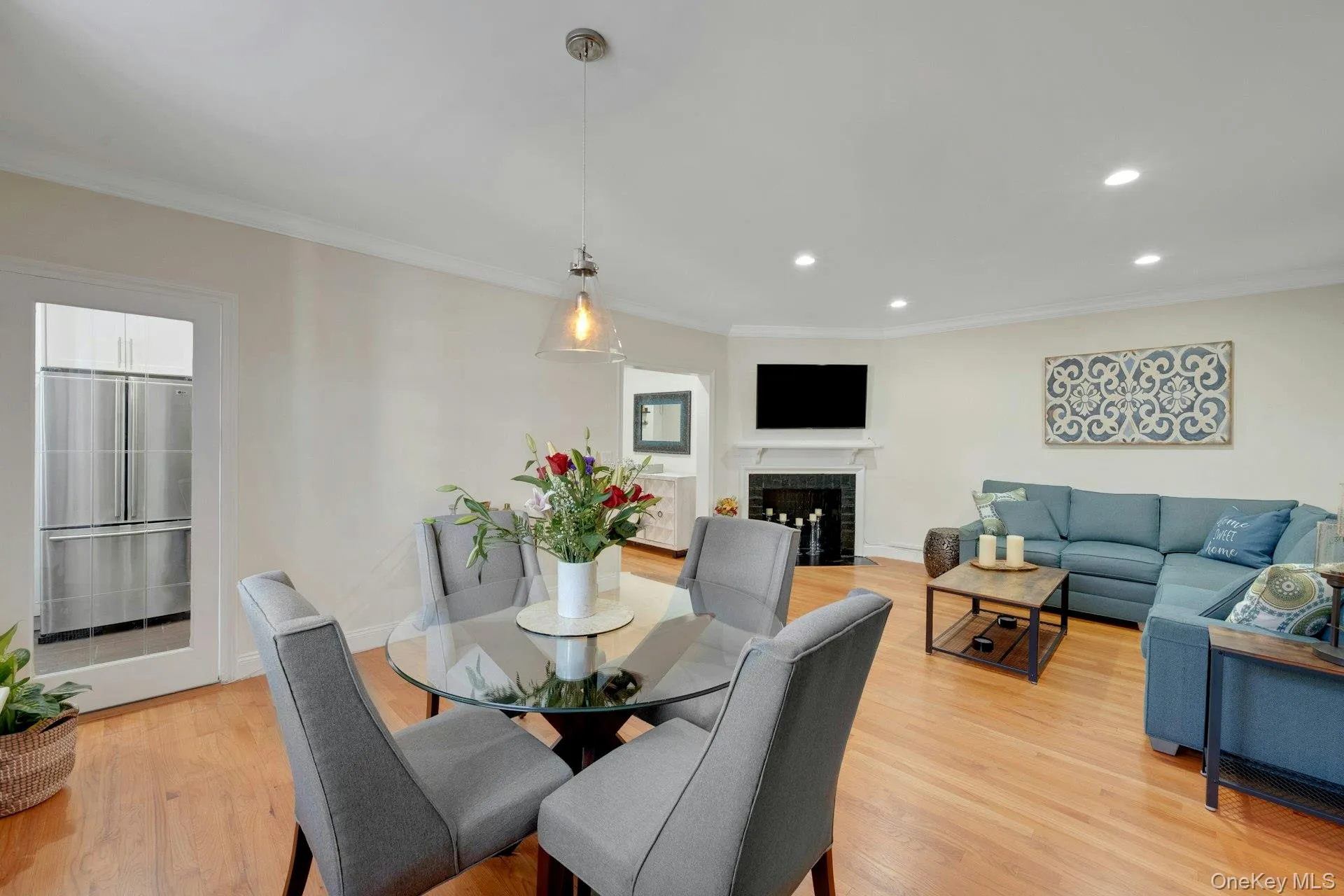 Dining room featuring a fireplace, ornamental molding, recessed lighting, and hardwood floors Dining room featuring a fireplace, ornamental molding, recessed lighting, and hardwood floors