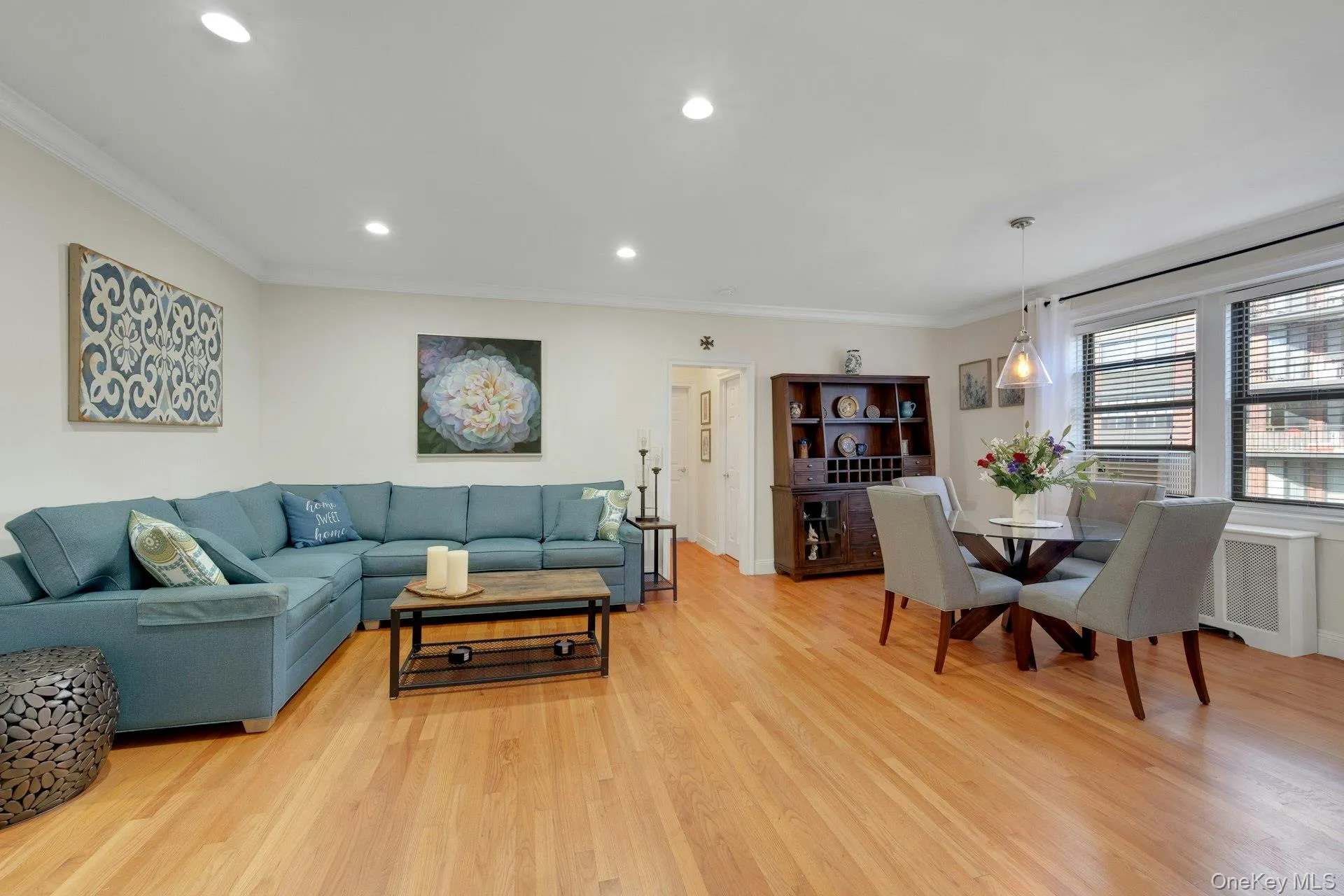 Living area featuring ornamental molding, light wood-style flooring, recessed lighting, and radiator heating unit Living area featuring ornamental molding, light wood-style flooring, recessed lighting, and radiator heating unit