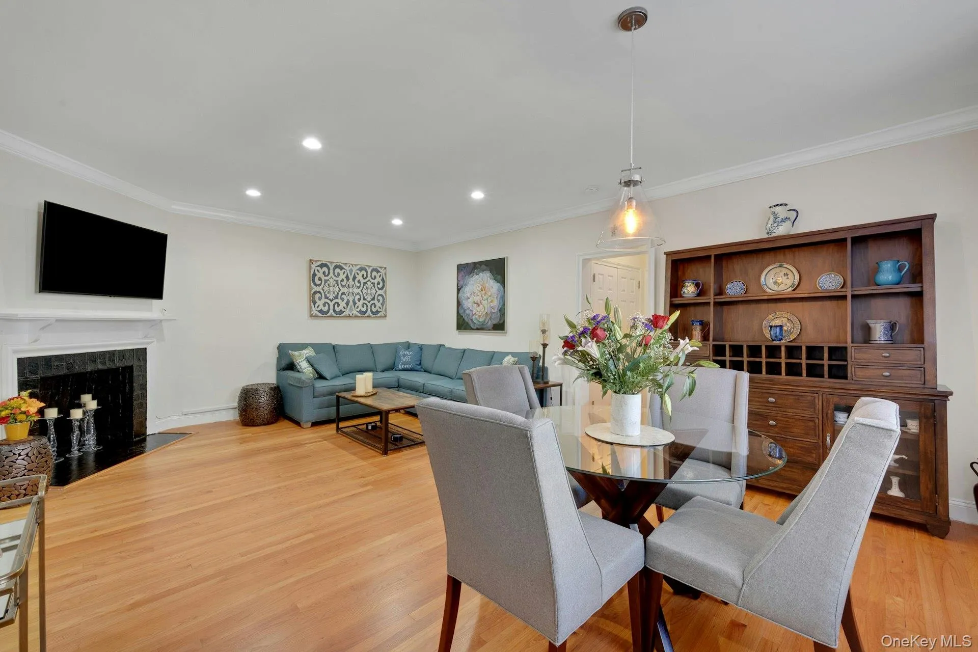 Dining room with ornamental molding, recessed lighting, light wood finished floors, and a fireplace Dining room with ornamental molding, recessed lighting, light wood finished floors, and a fireplace