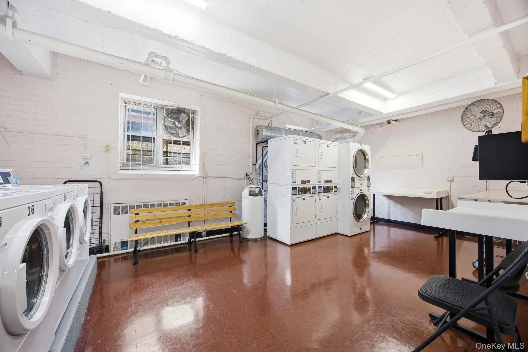 Shared laundry room with stacked washer and clothes dryer and radiator heating unit. Shared laundry room with stacked washer and clothes dryer and radiator heating unit.