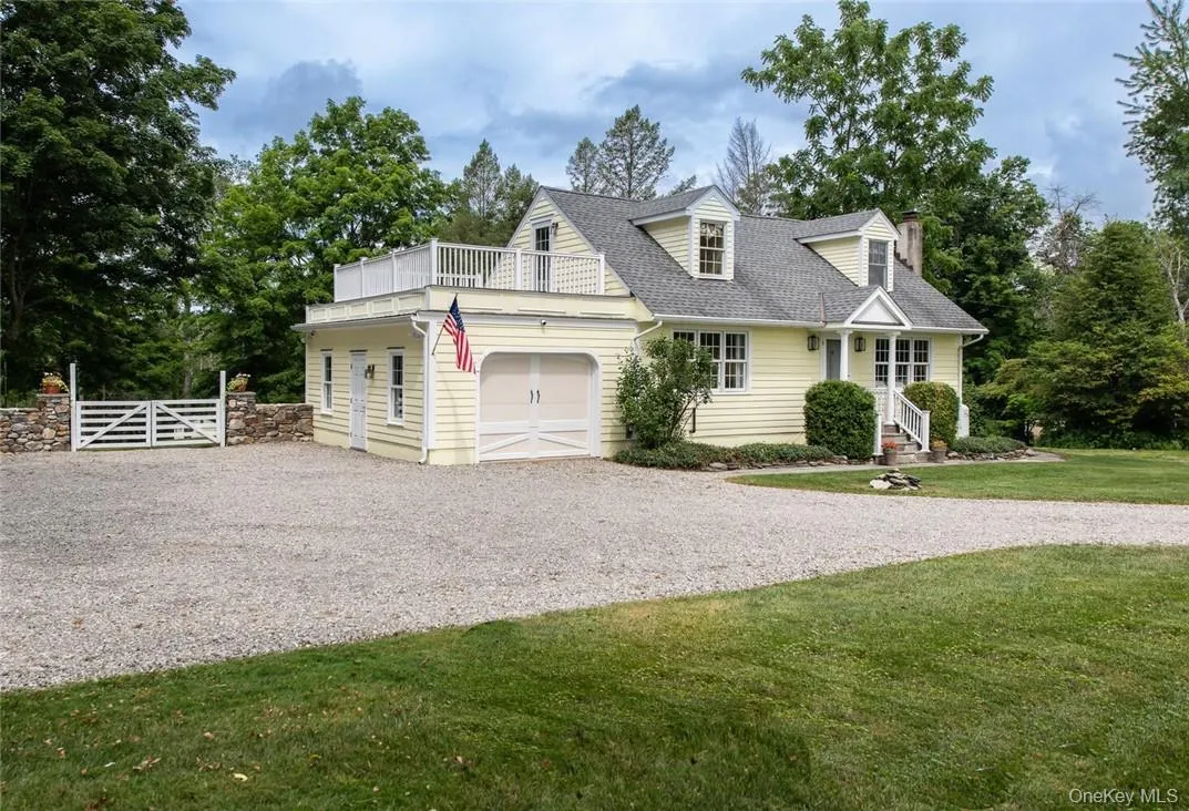 Cape cod-style house featuring a garage, a balcony, and a front lawn Cape cod-style house featuring a garage, a balcony, and a front lawn