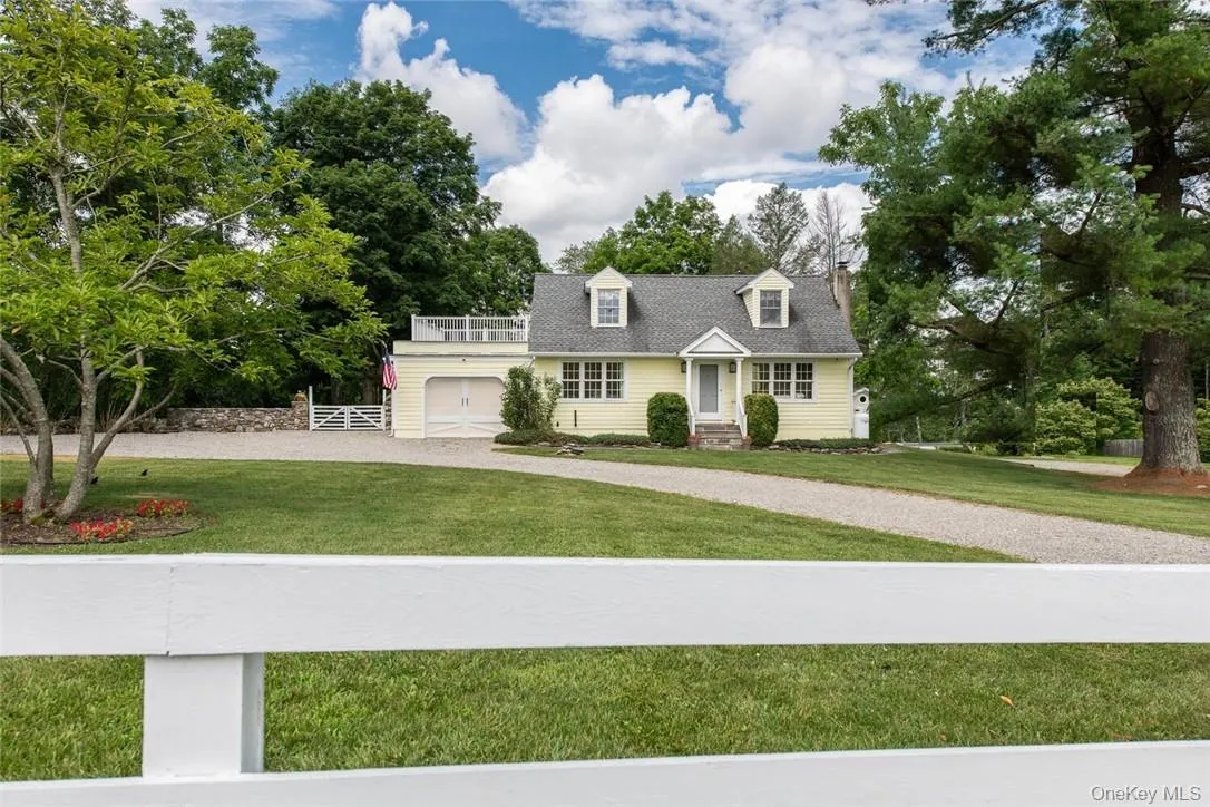 New england style home featuring a garage and a front yard New england style home featuring a garage and a front yard