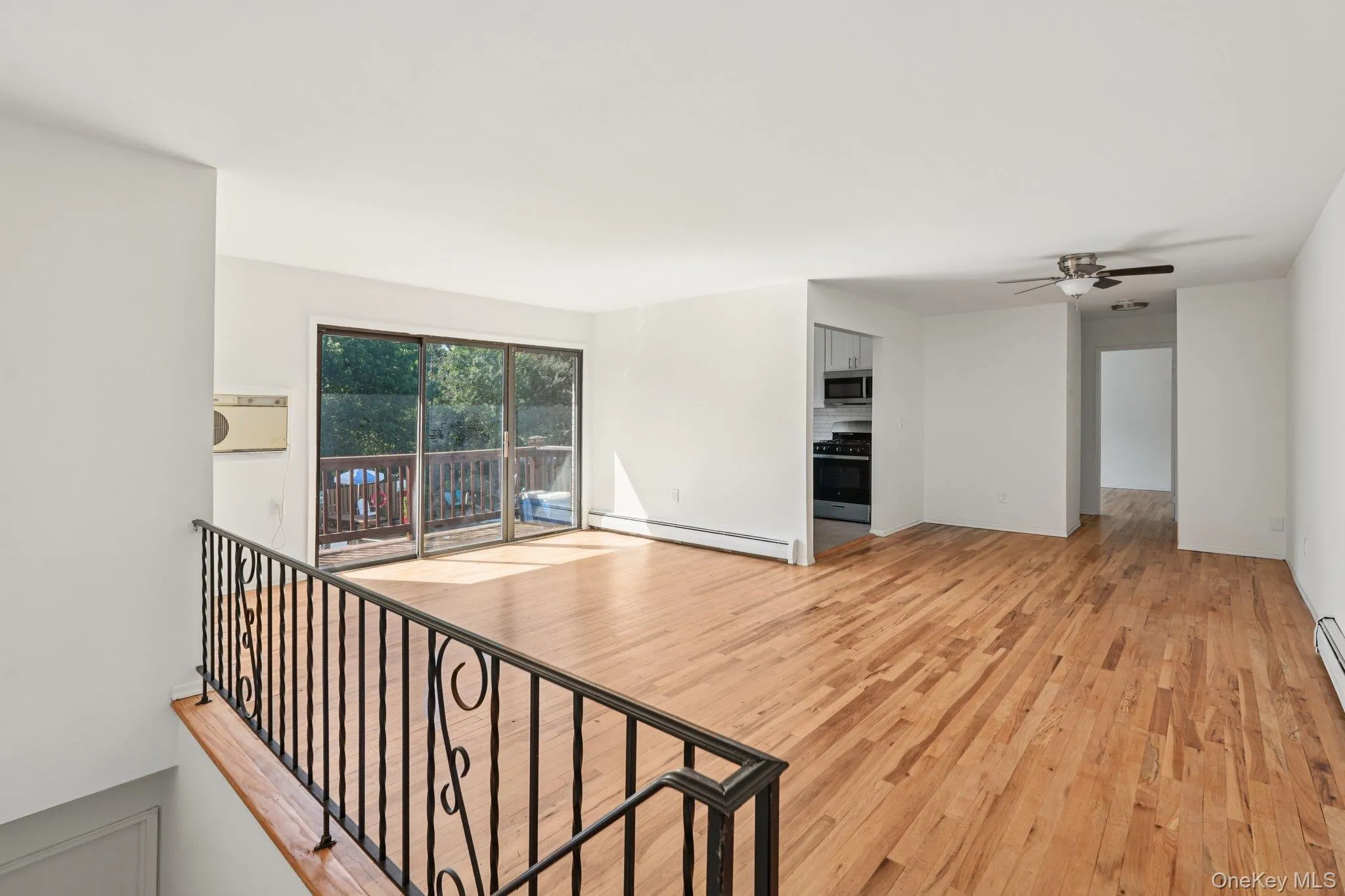 Unfurnished living room with light wood-type flooring, ceiling fan, and baseboard heating Unfurnished living room with light wood-type flooring, ceiling fan, and baseboard heating