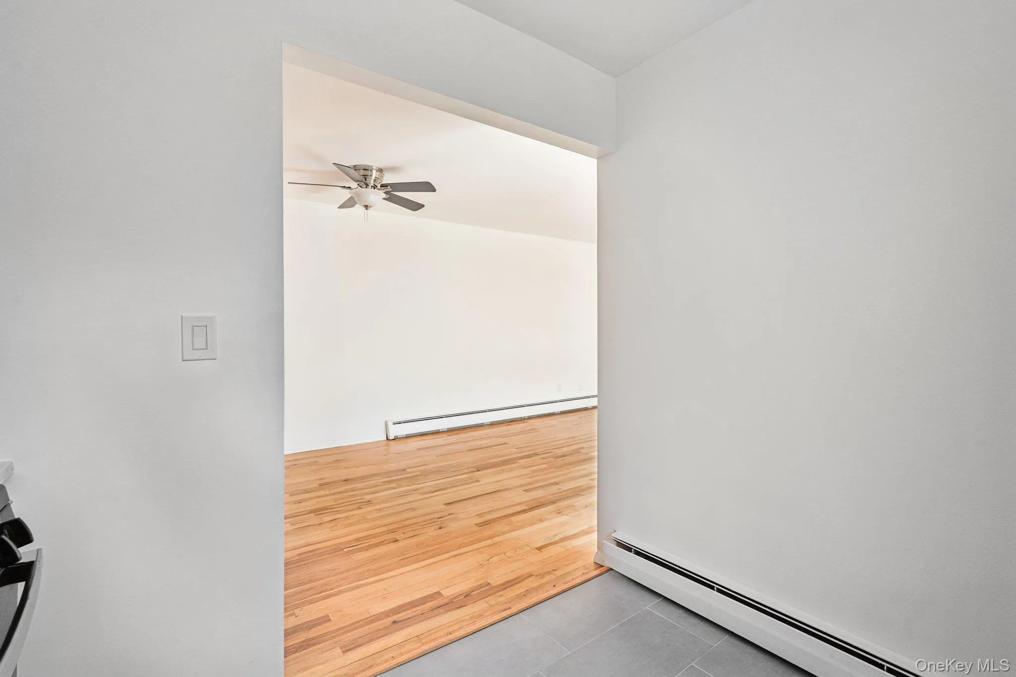 Unfurnished room featuring a baseboard heating unit, light tile patterned floors, and ceiling fan Unfurnished room featuring a baseboard heating unit, light tile patterned floors, and ceiling fan