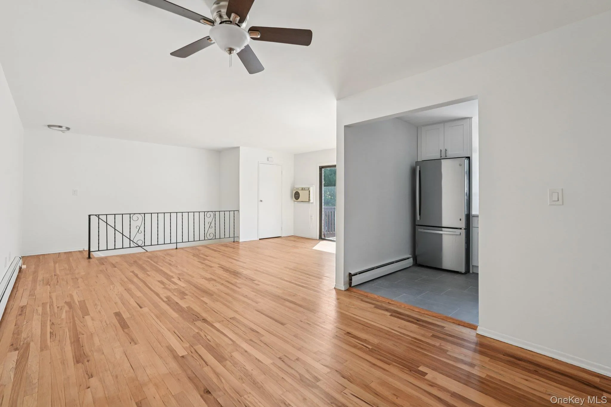 Unfurnished room with light wood-style floors, baseboard heating, a ceiling fan, and a baseboard heating unit Unfurnished room with light wood-style floors, baseboard heating, a ceiling fan, and a baseboard heating unit