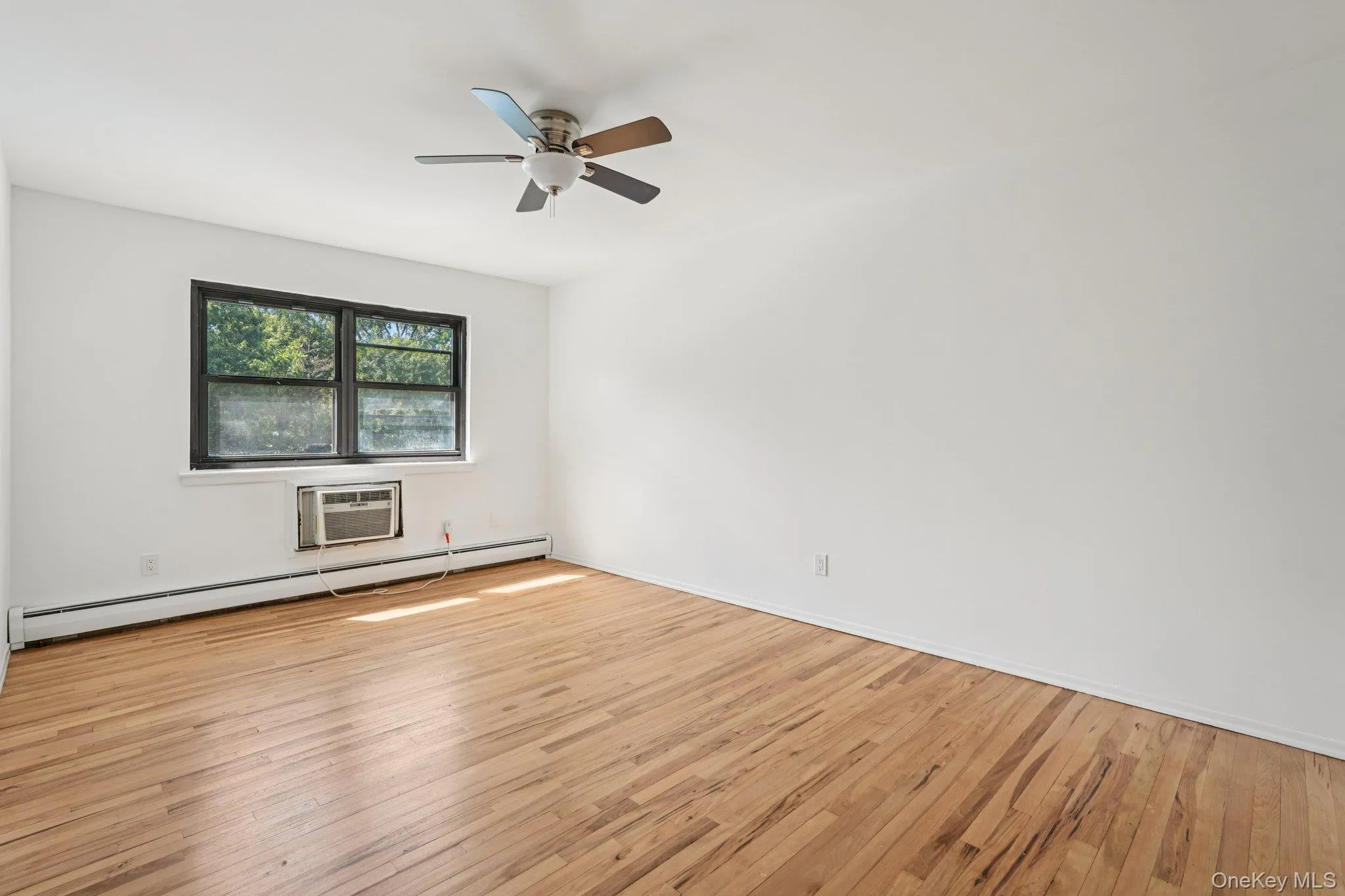 Spare room with light wood-style floors, a baseboard radiator, and a ceiling fan Spare room with light wood-style floors, a baseboard radiator, and a ceiling fan