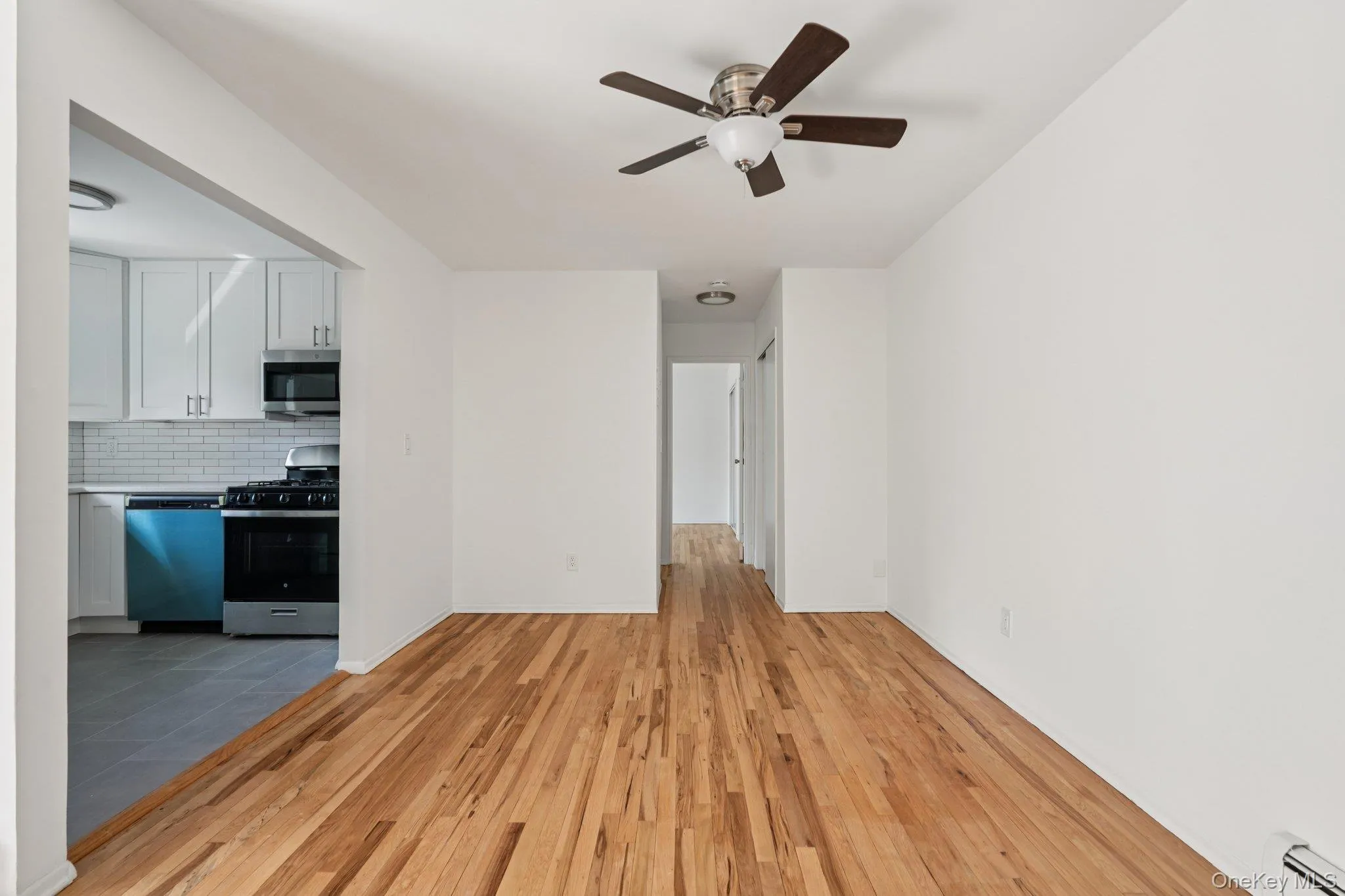 Unfurnished living room featuring light wood-style flooring, a baseboard radiator, and a ceiling fan Unfurnished living room featuring light wood-style flooring, a baseboard radiator, and a ceiling fan