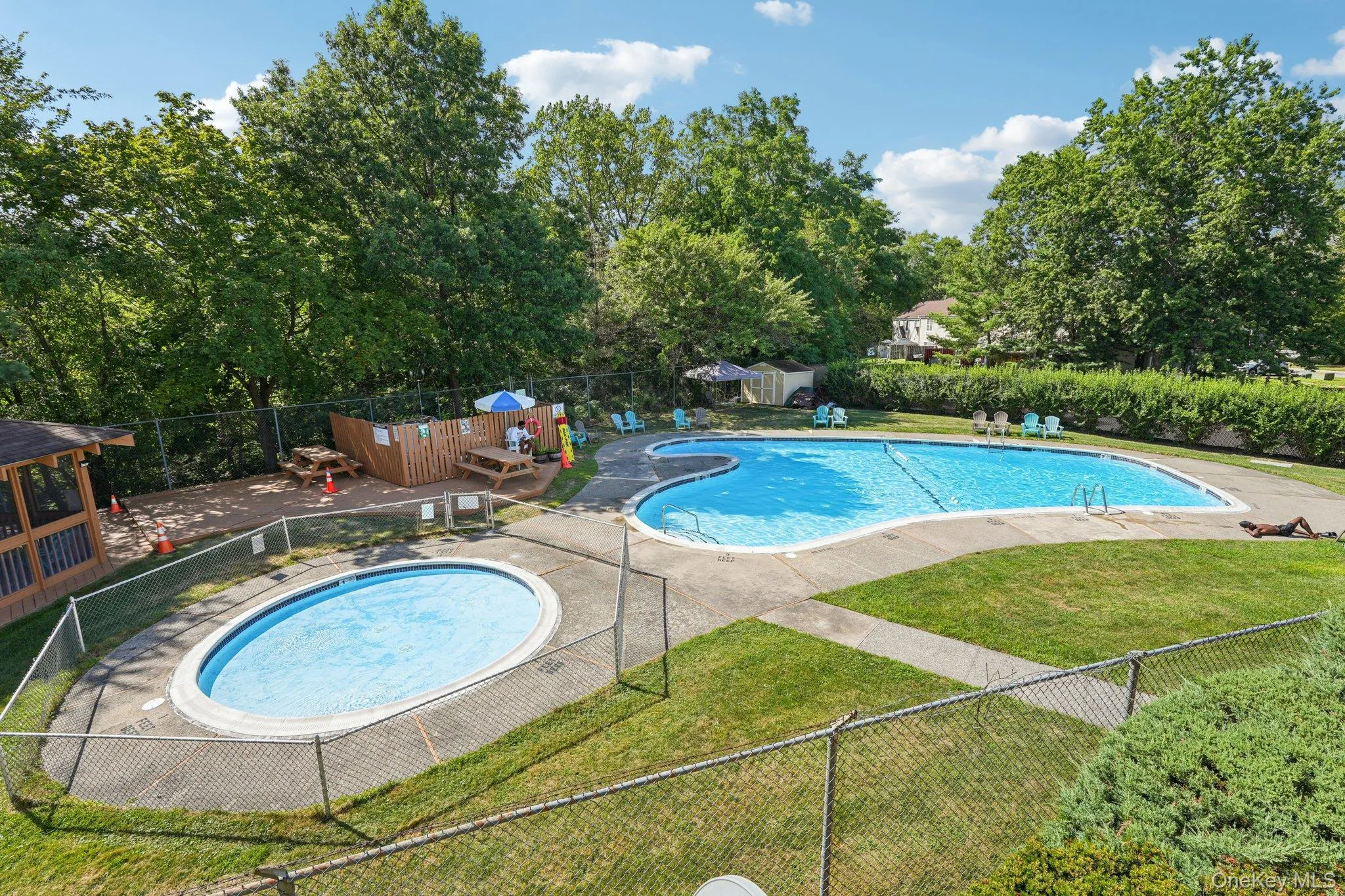 Community pool with a patio area and view of wooded area Community pool with a patio area and view of wooded area
