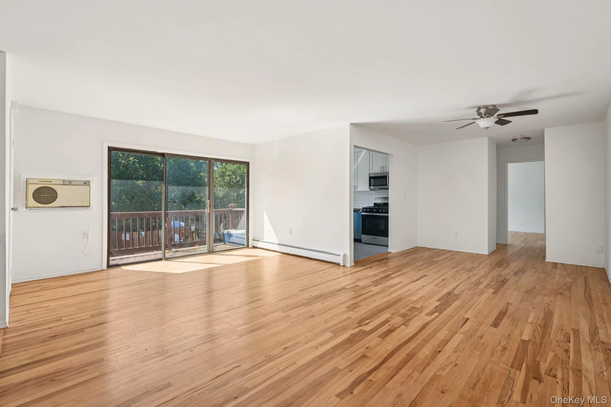 Unfurnished living room with light wood-type flooring, a baseboard heating unit, and a ceiling fan Unfurnished living room with light wood-type flooring, a baseboard heating unit, and a ceiling fan