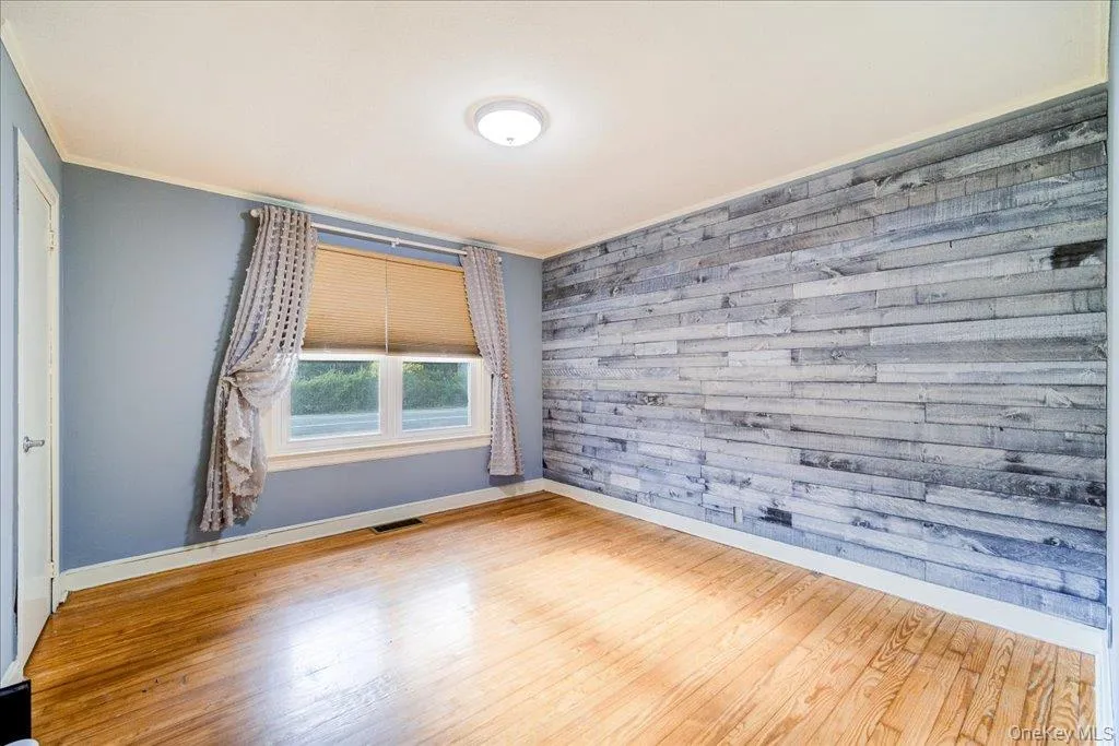 Primary bedroom with wood flooring and ornamental molding Primary bedroom with wood flooring and ornamental molding