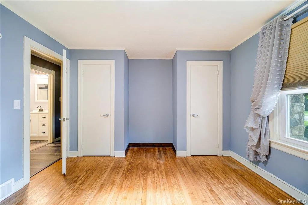 Bedroom with crown molding, sink, light hardwood / wood-style flooring, and a closet Bedroom with crown molding, sink, light hardwood / wood-style flooring, and a closet