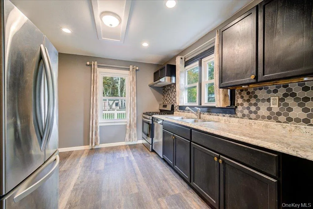 Kitchen with a healthy amount of sunlight, sink, light hardwood / wood-style flooring, and stainless steel appliances Kitchen with a healthy amount of sunlight, sink, light hardwood / wood-style flooring, and stainless steel appliances
