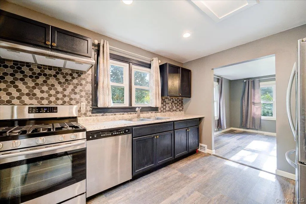 Kitchen with appliances with stainless steel finishes, backsplash, light wood-type flooring, and sink Kitchen with appliances with stainless steel finishes, backsplash, light wood-type flooring, and sink