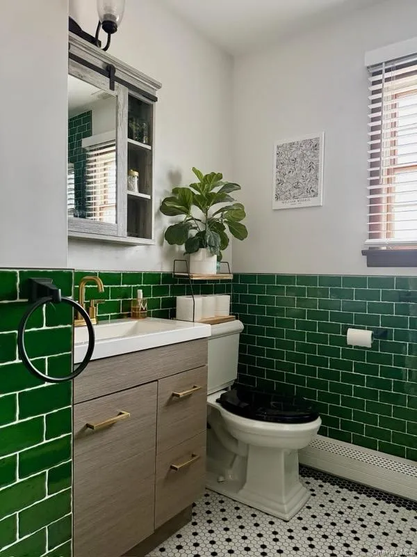Bathroom featuring tile walls, a wainscoted wall, toilet, tile patterned floors, and vanity Bathroom featuring tile walls, a wainscoted wall, toilet, tile patterned floors, and vanity