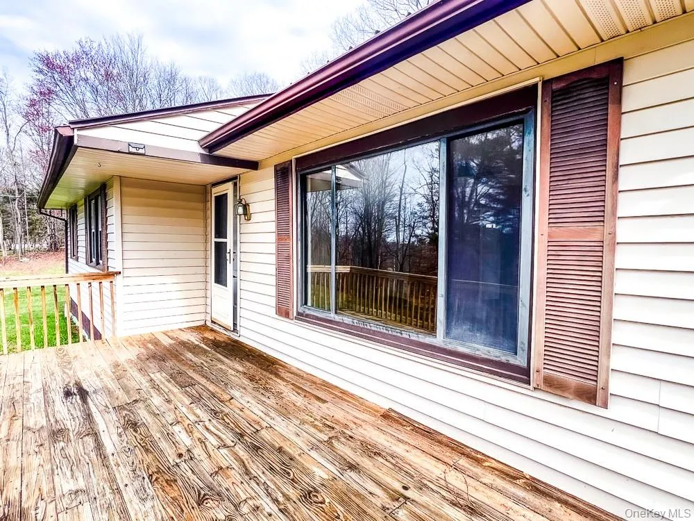 The property features an exterior with light-colored siding, a wooden deck, and a sliding glass door The property features an exterior with light-colored siding, a wooden deck, and a sliding glass door