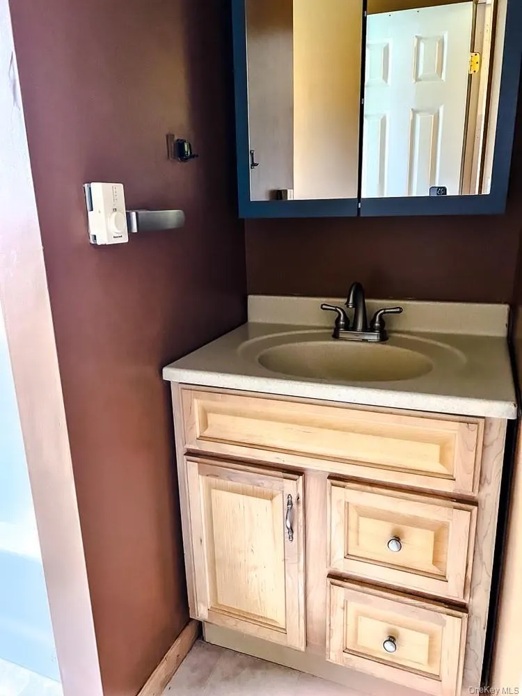 The vanity features a light-colored countertop with an integrated sink and a two-handle faucet The vanity features a light-colored countertop with an integrated sink and a two-handle faucet