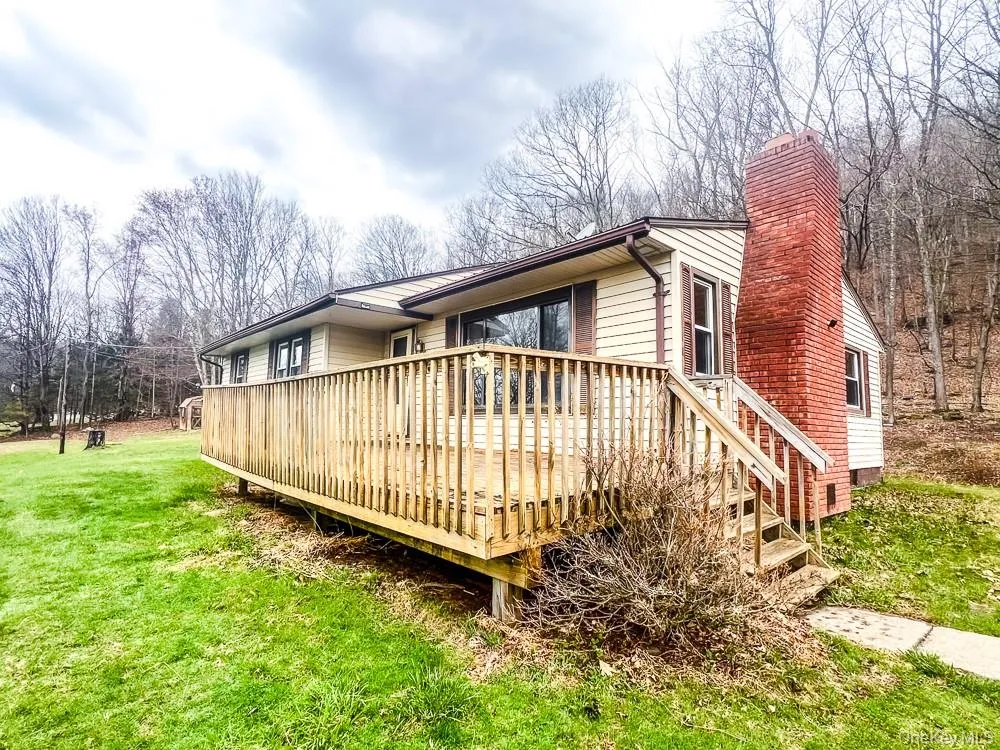 The property features a wood deck with a railing and steps, leading to a concrete pathway The property features a wood deck with a railing and steps, leading to a concrete pathway