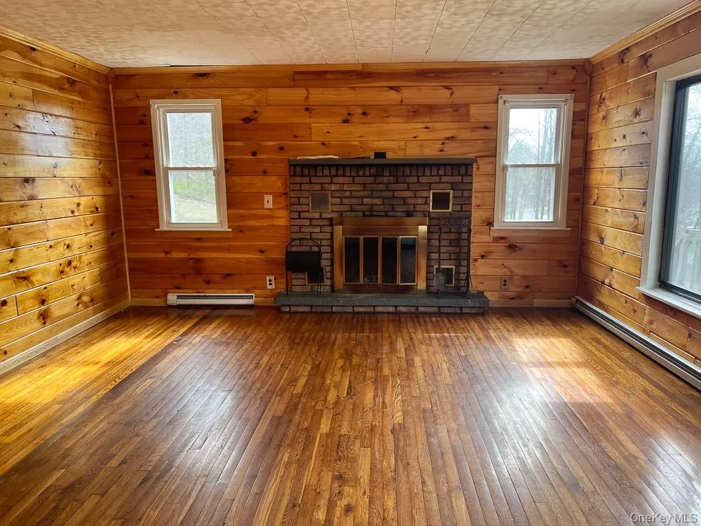 The living area features wood paneling, hardwood floors, and a brick fireplace The living area features wood paneling, hardwood floors, and a brick fireplace