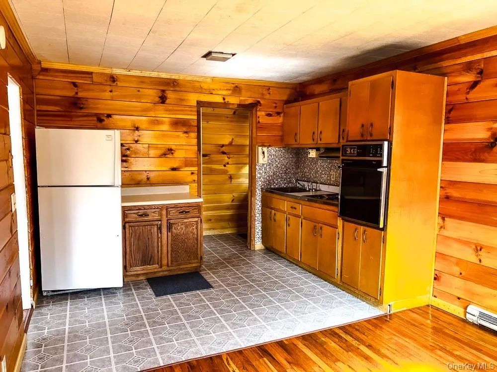 Kitchen featuring wood paneling, an integrated oven, and a built-in stovetop Kitchen featuring wood paneling, an integrated oven, and a built-in stovetop