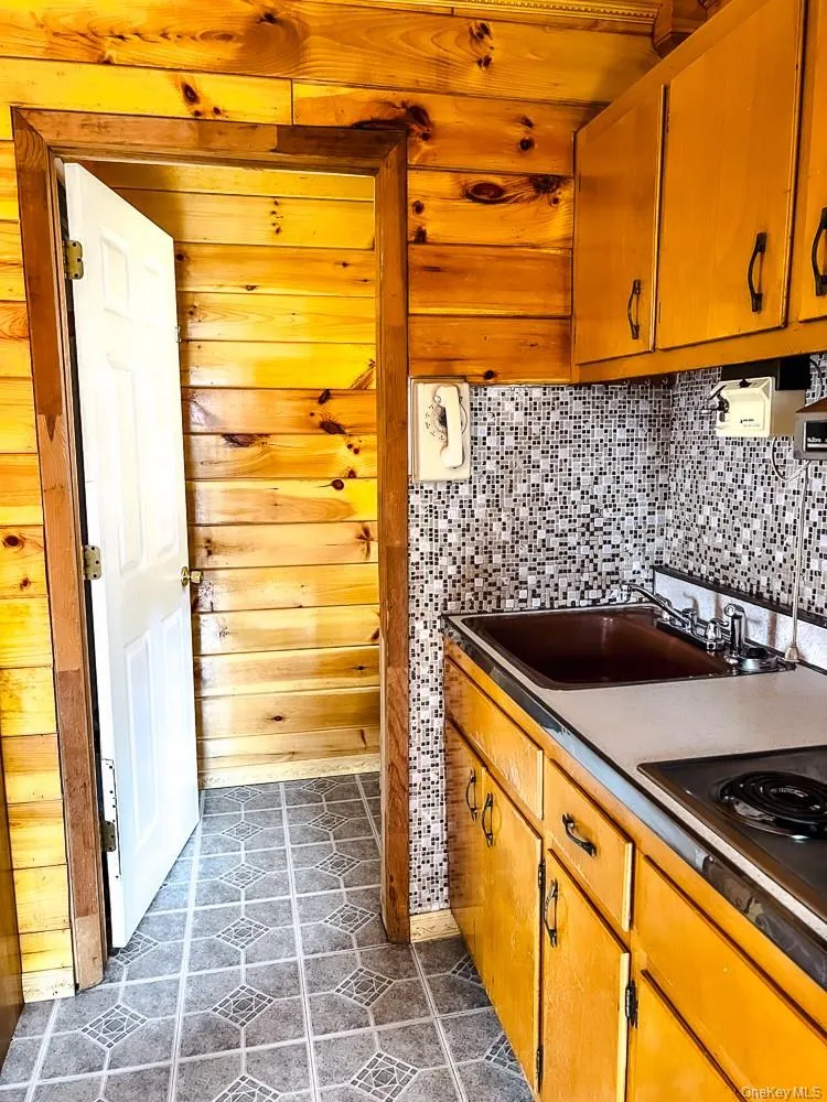 The kitchen features wooden cabinetry, a mosaic tile backsplash, and a built-in cooktop The kitchen features wooden cabinetry, a mosaic tile backsplash, and a built-in cooktop