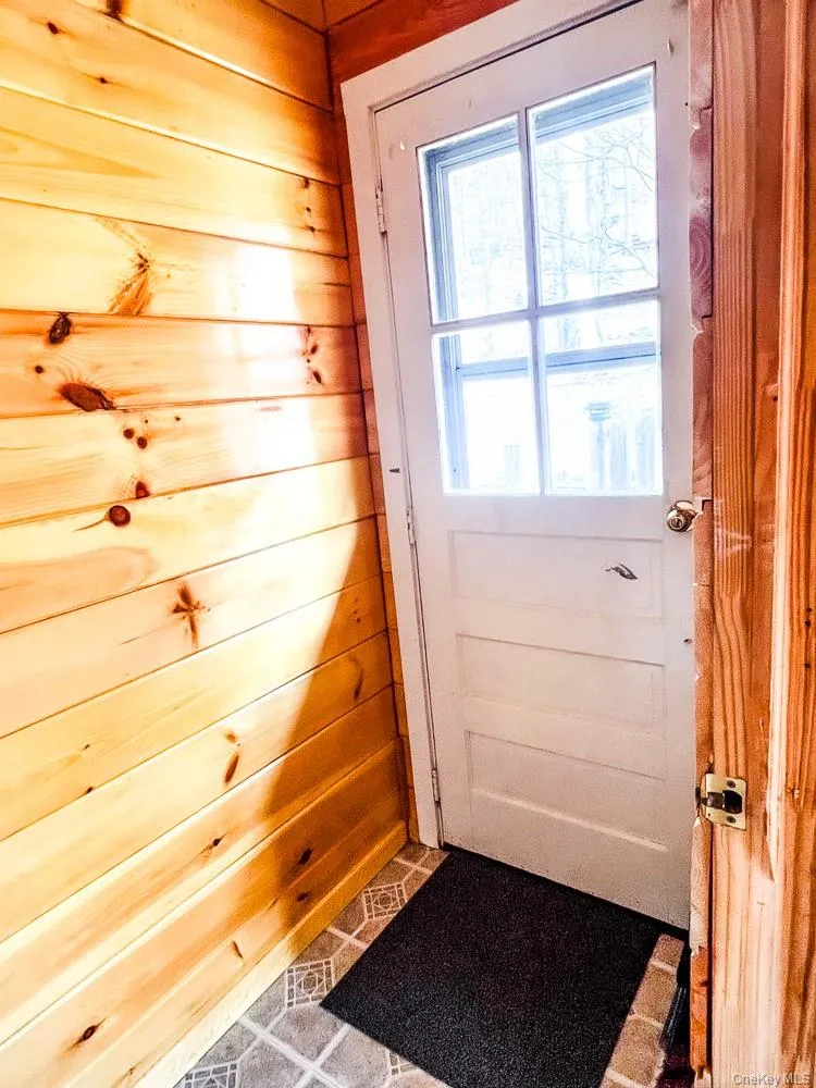 This entryway features natural wood paneling, a white door with glass panes, and patterned floor tiles This entryway features natural wood paneling, a white door with glass panes, and patterned floor tiles