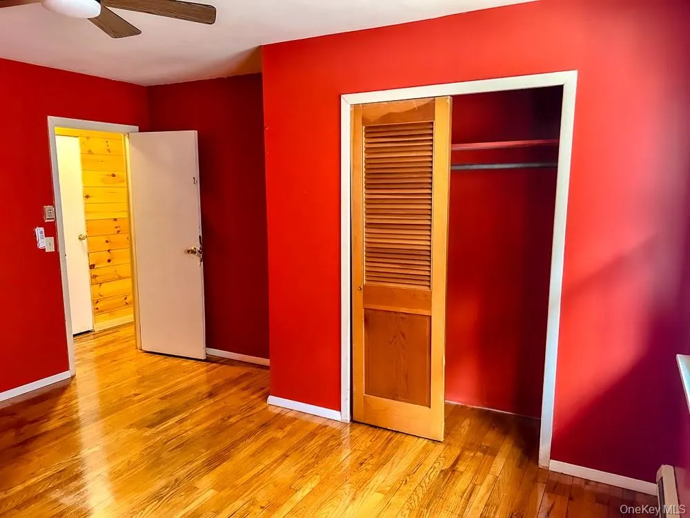 This room features hardwood floors, a ceiling fan, and a closet with a louvered bi-fold door This room features hardwood floors, a ceiling fan, and a closet with a louvered bi-fold door
