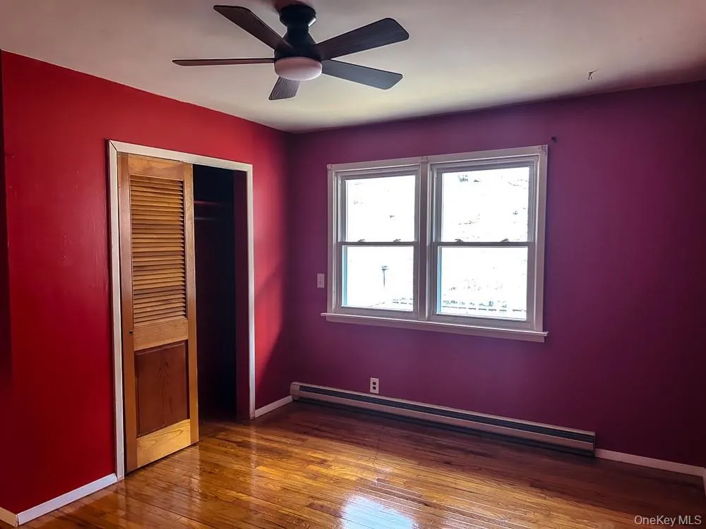 This room features vibrant red walls, polished hardwood floors, and a ceiling fan This room features vibrant red walls, polished hardwood floors, and a ceiling fan