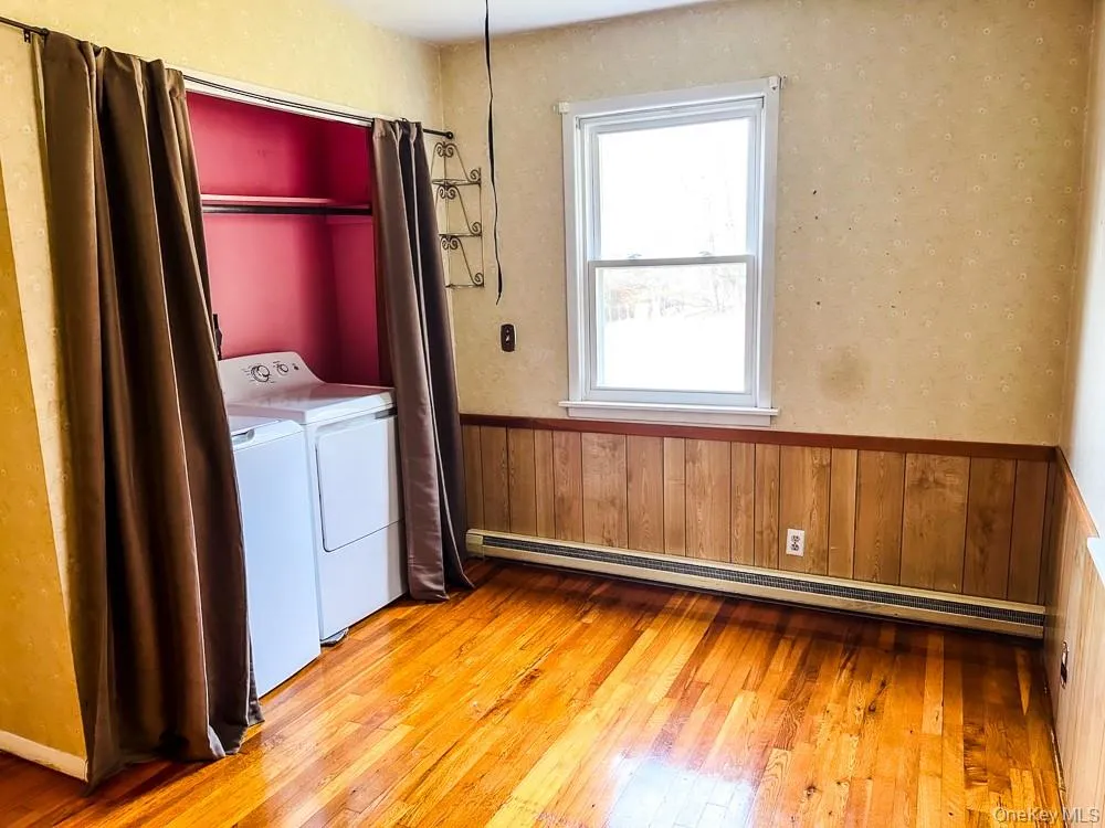 This space features hardwood floors, a window providing natural light, and a dedicated area for laundry appliances This space features hardwood floors, a window providing natural light, and a dedicated area for laundry appliances