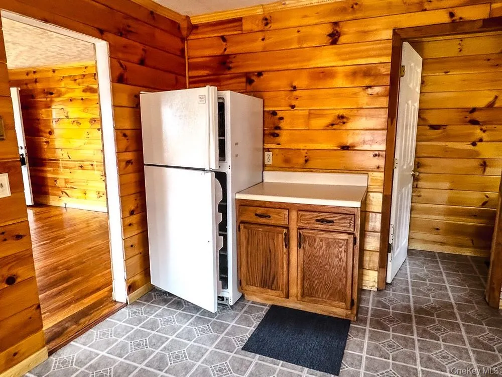 The property features a kitchen area with wood paneling on the walls, a white refrigerator, and a cabinet with a countertop The property features a kitchen area with wood paneling on the walls, a white refrigerator, and a cabinet with a countertop