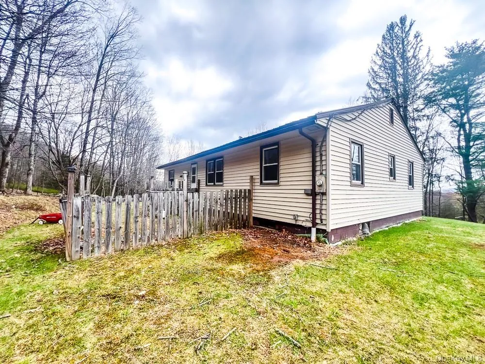 The property features light-colored horizontal siding, dark-trimmed windows, and a partially fenced yard The property features light-colored horizontal siding, dark-trimmed windows, and a partially fenced yard