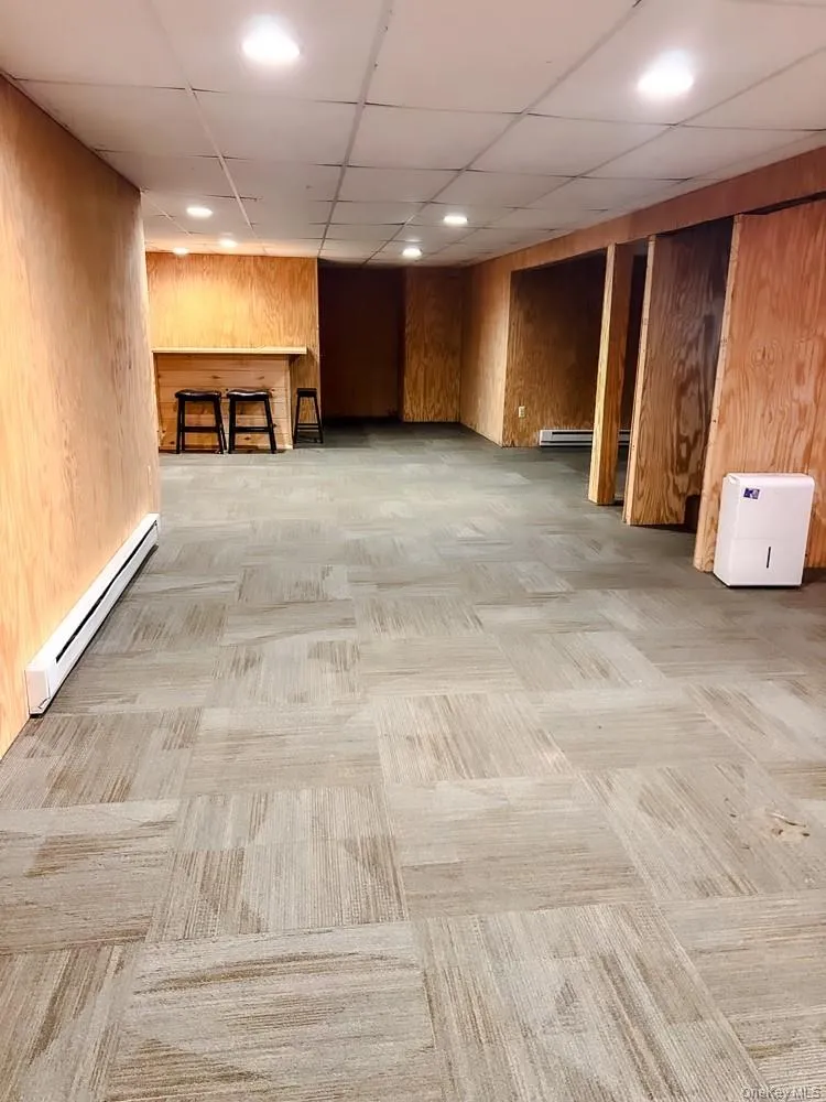 Spacious room featuring paneled walls, recessed lighting, and a patterned carpet floor Spacious room featuring paneled walls, recessed lighting, and a patterned carpet floor