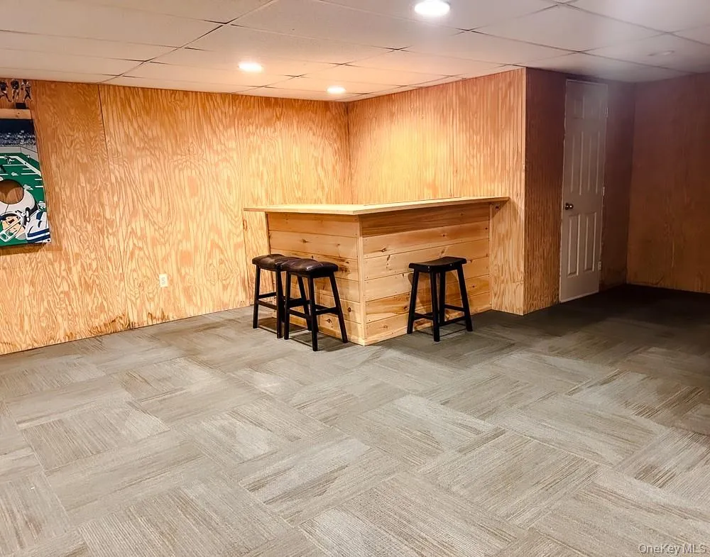 The property features a built-in wooden bar with recessed lighting, complemented by light-toned paneled walls The property features a built-in wooden bar with recessed lighting, complemented by light-toned paneled walls