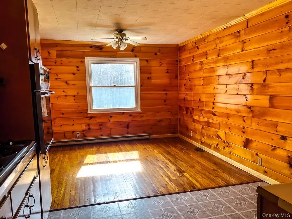 This room features wood paneled walls, a window providing natural light, and a ceiling fan This room features wood paneled walls, a window providing natural light, and a ceiling fan