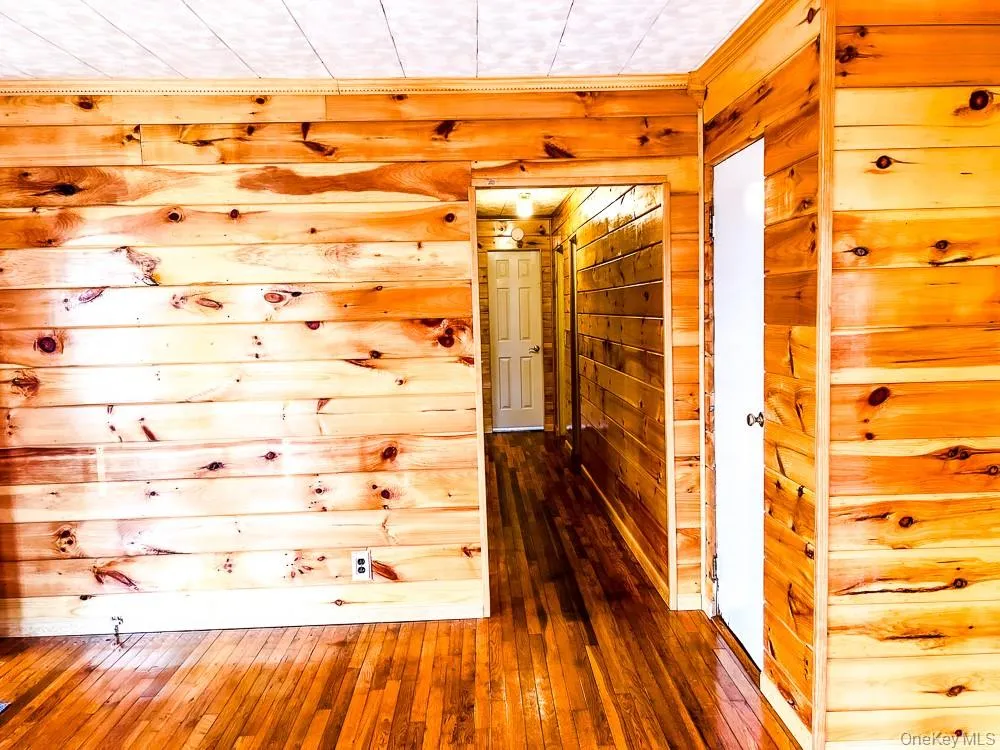 Interior space featuring natural wood paneling on the walls and hardwood floors Interior space featuring natural wood paneling on the walls and hardwood floors