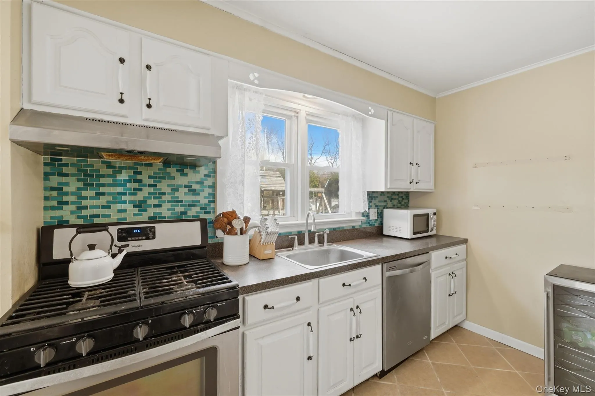 highly functional kitchen looking out to the backyard with white cabinets, stainless steel appliances and great natural light highly functional kitchen looking out to the backyard with white cabinets, stainless steel appliances and great natural light