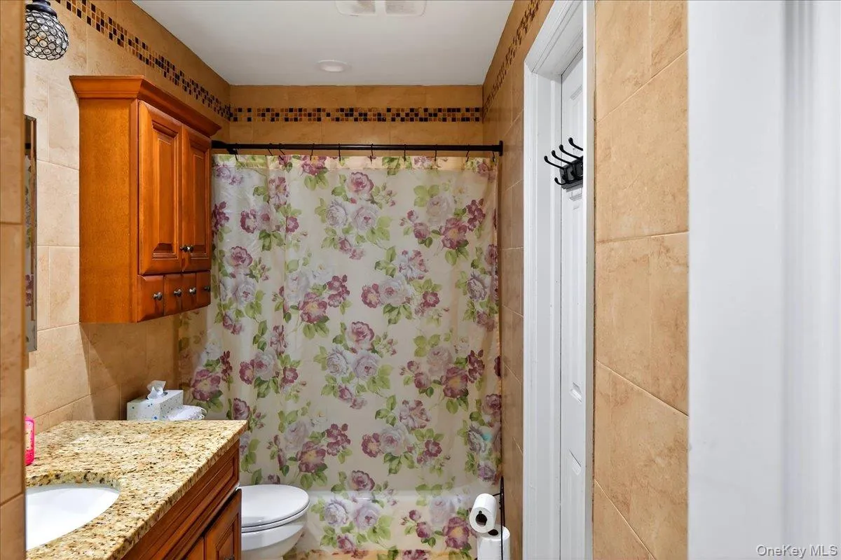 Bathroom with a shower with shower curtain, vanity, and tile walls Bathroom with a shower with shower curtain, vanity, and tile walls