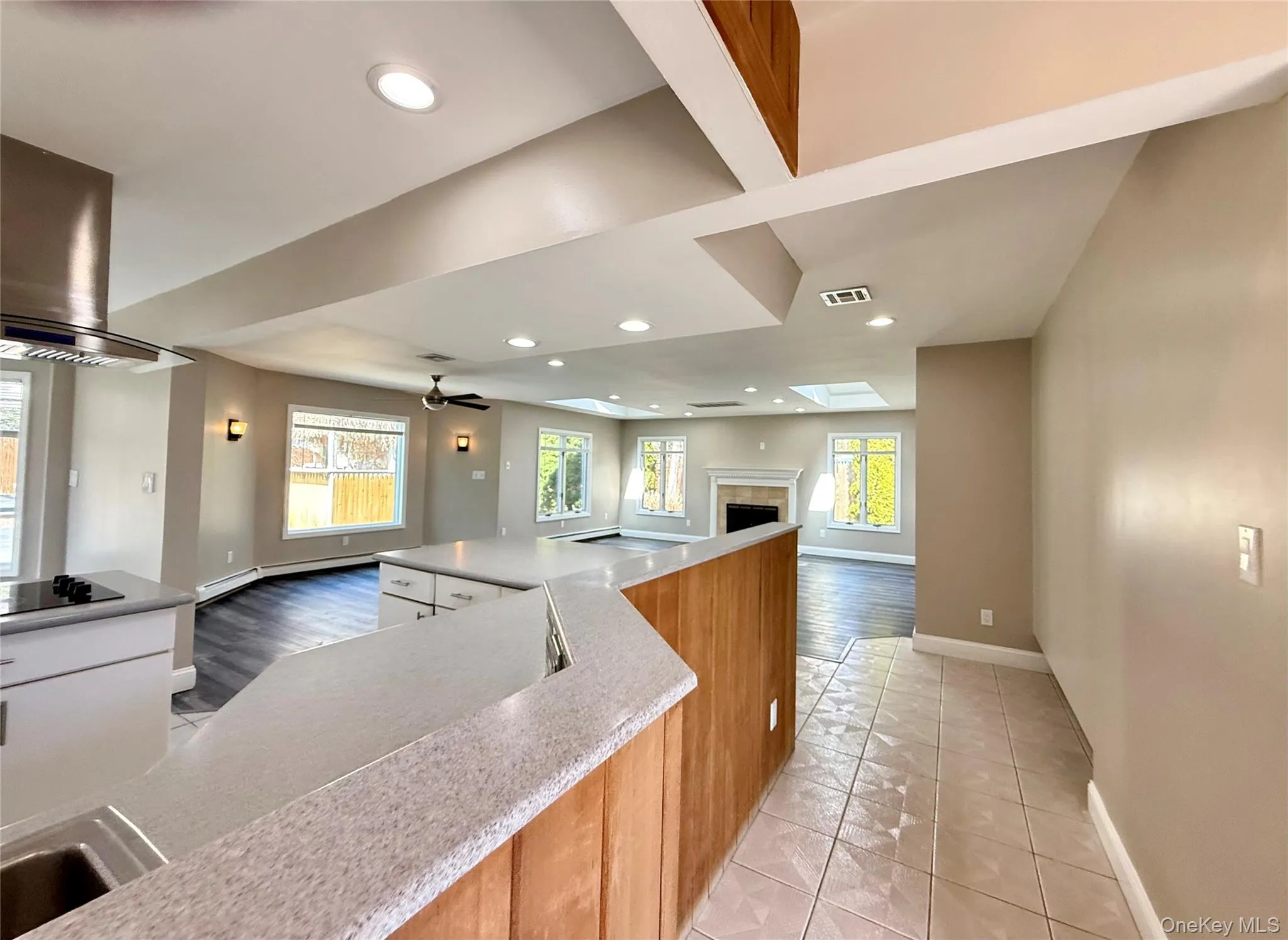 Kitchen with open floor plan, exhaust hood, recessed lighting, a tile fireplace, and light tile patterned flooring Kitchen with open floor plan, exhaust hood, recessed lighting, a tile fireplace, and light tile patterned flooring