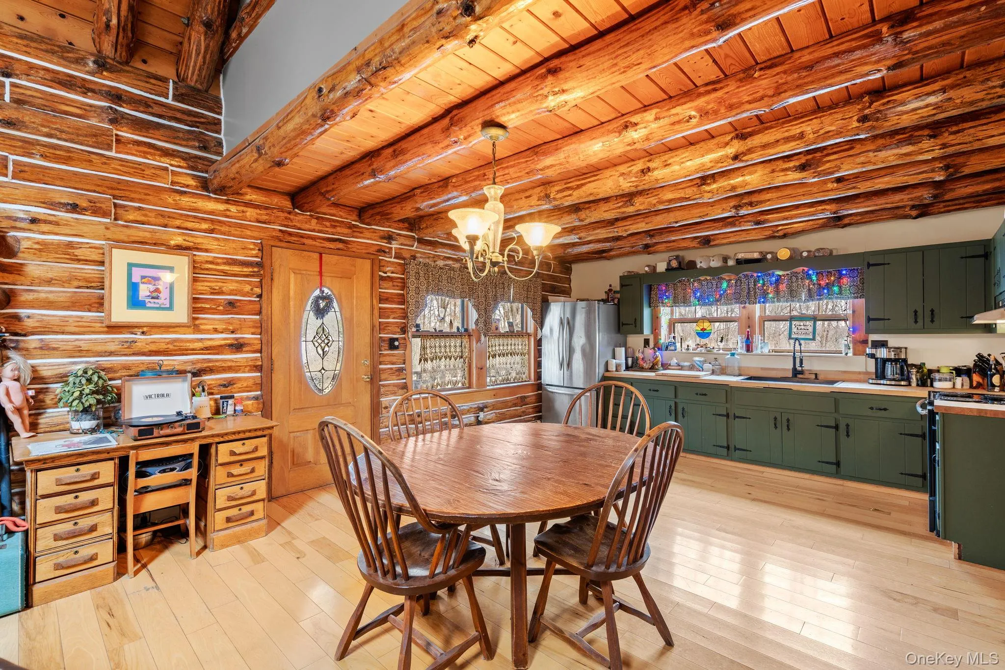 Dining area with light wood-type flooring, a wood ceiling with exposed beams, a chandelier, and log walls Dining area with light wood-type flooring, a wood ceiling with exposed beams, a chandelier, and log walls