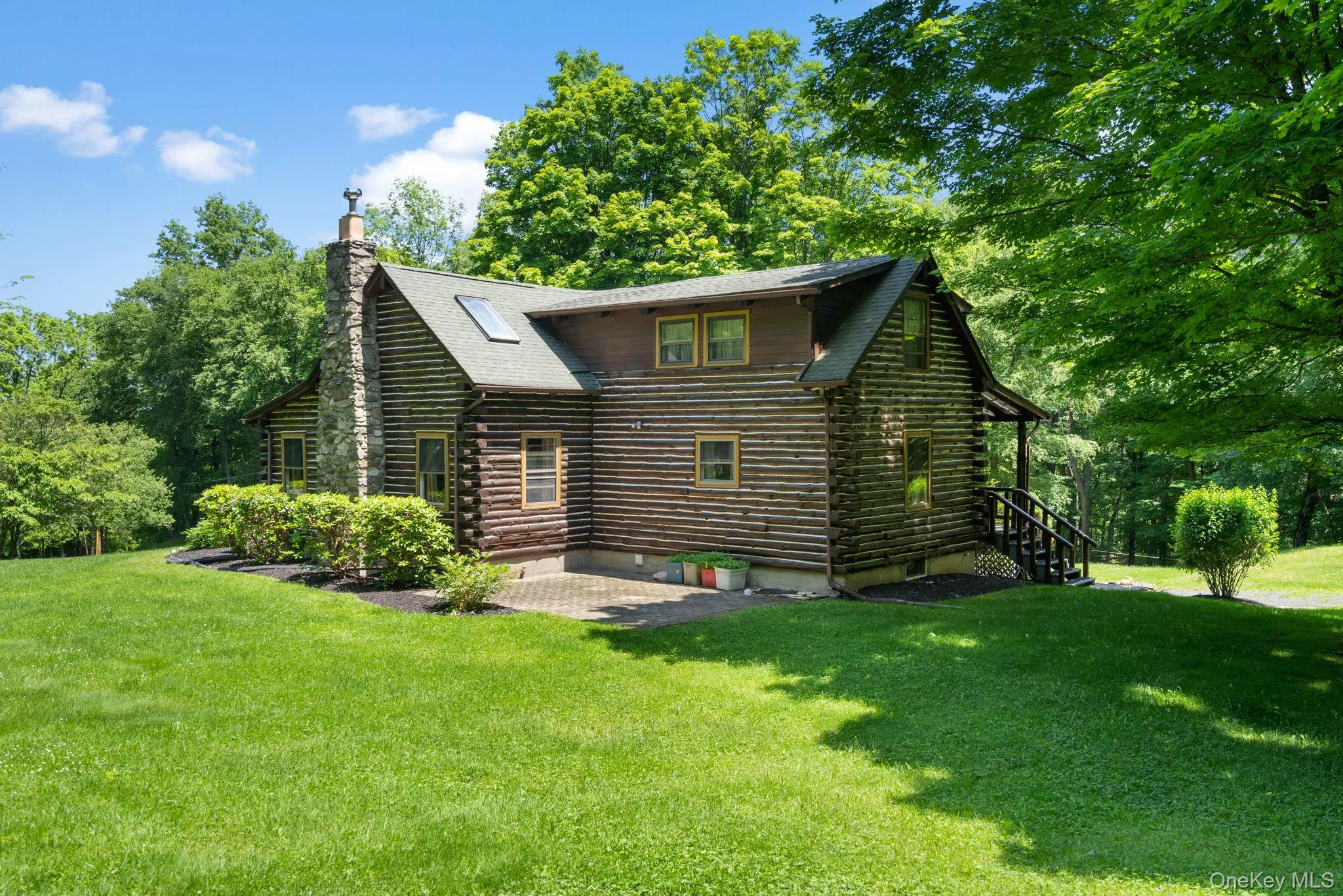 Rear view of property featuring a lawn, a patio area, log siding, and a chimney Rear view of property featuring a lawn, a patio area, log siding, and a chimney