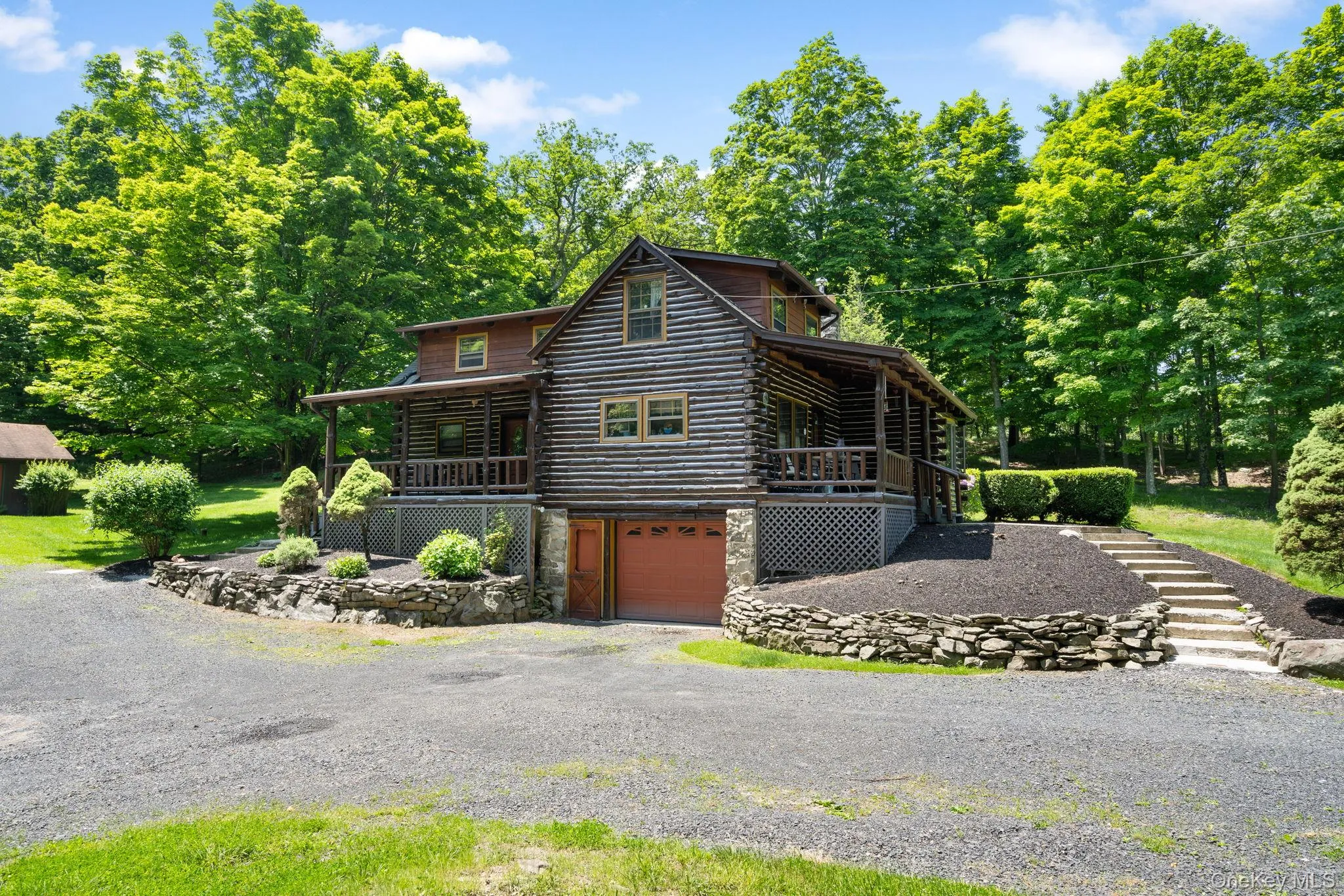 Log cabin with log siding, a garage, driveway, stone siding, and covered porch Log cabin with log siding, a garage, driveway, stone siding, and covered porch