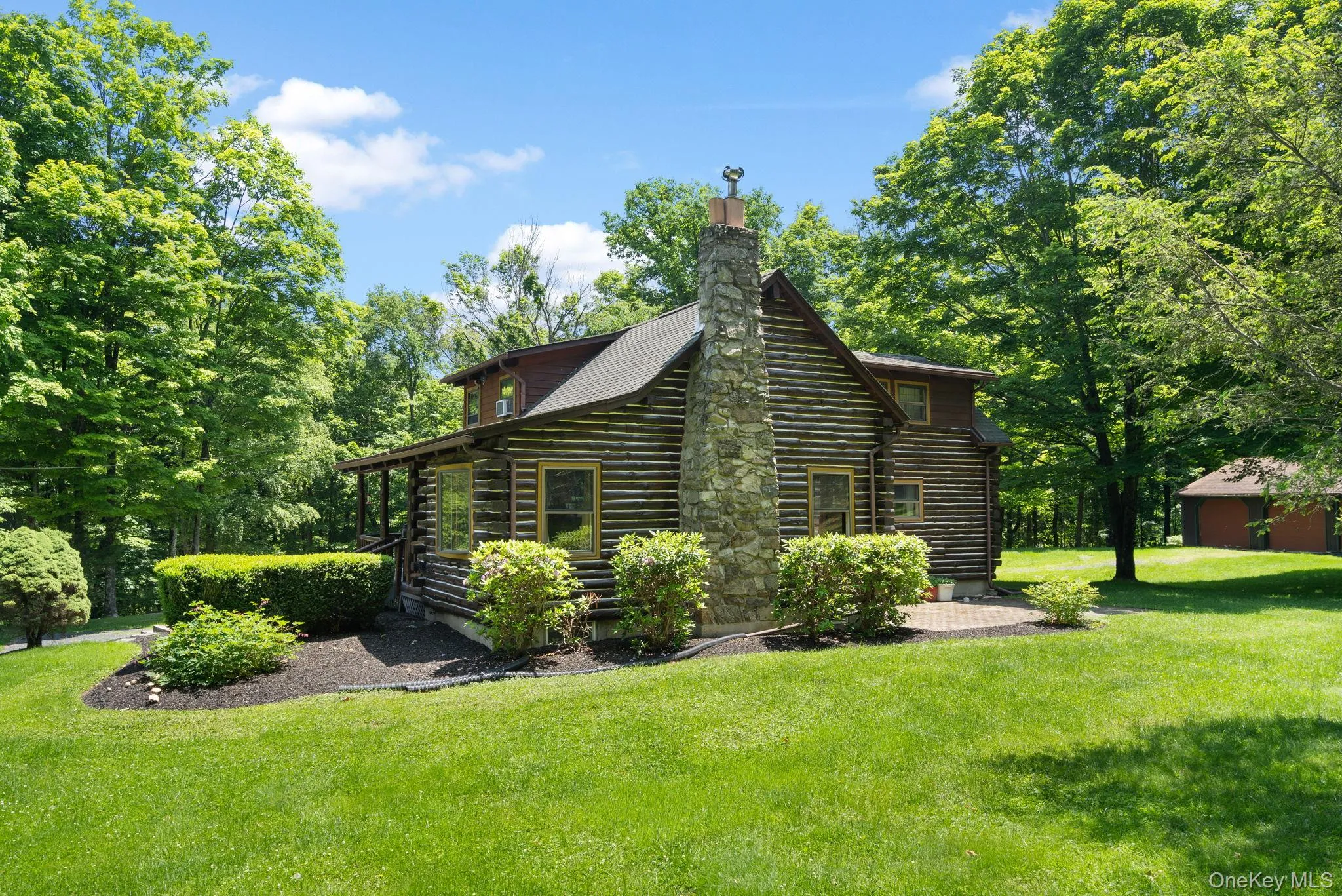 View of side of home with log siding, a lawn, and a chimney View of side of home with log siding, a lawn, and a chimney