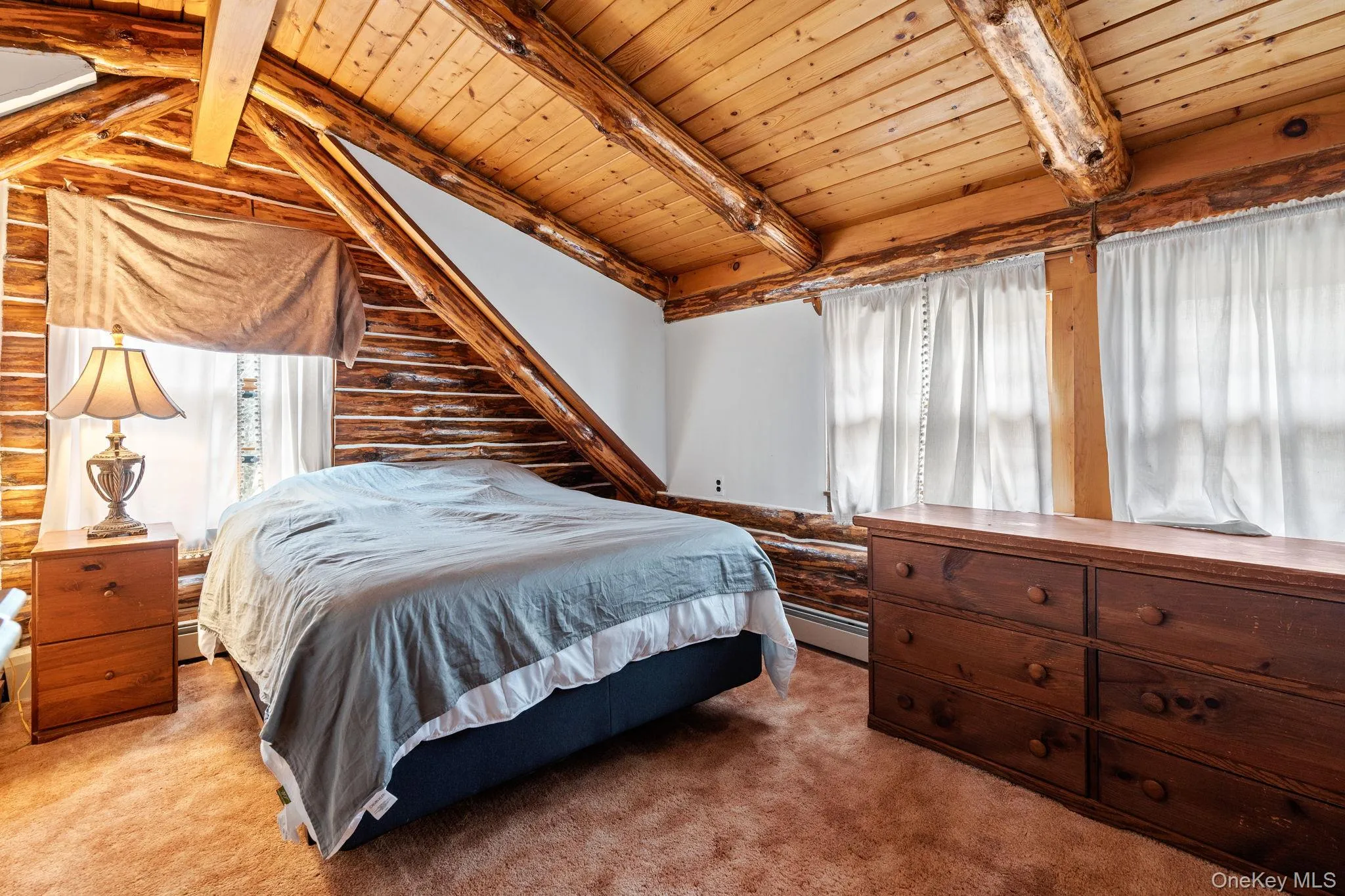 Carpeted bedroom featuring wood ceiling, log walls, and baseboard heating Carpeted bedroom featuring wood ceiling, log walls, and baseboard heating