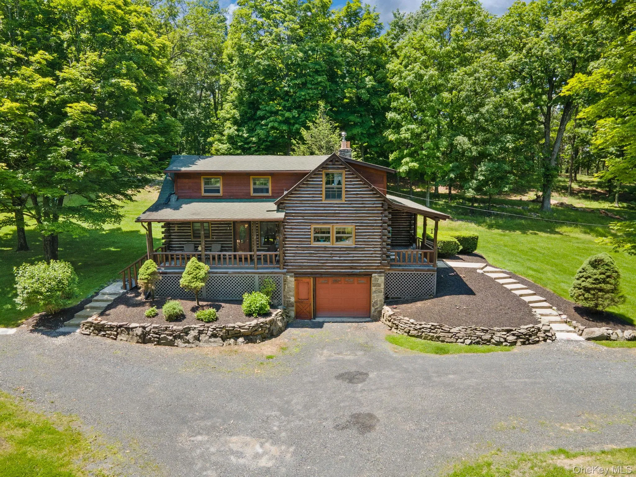 Log cabin with log exterior, covered porch, a garage, and gravel driveway Log cabin with log exterior, covered porch, a garage, and gravel driveway