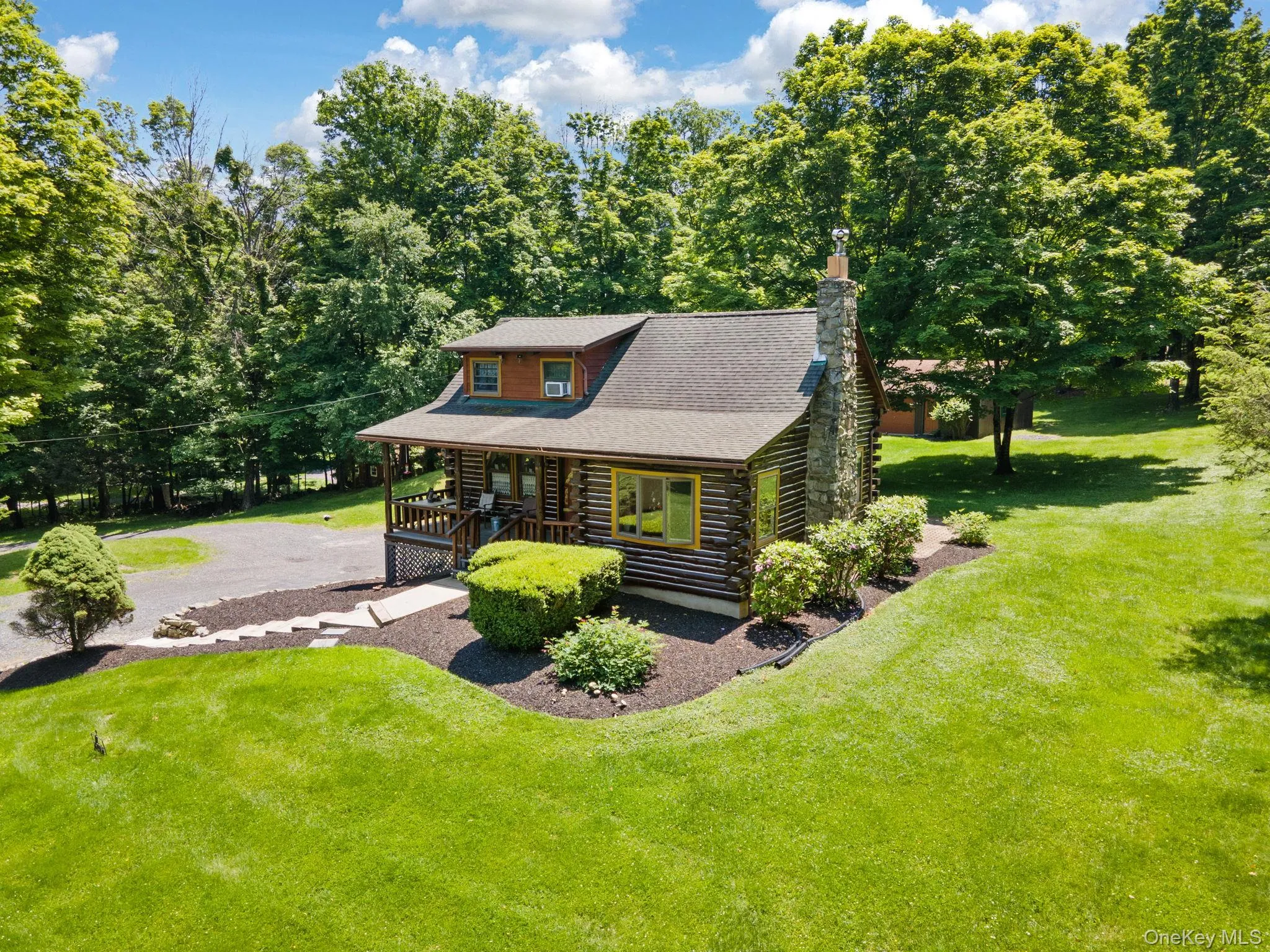 Log-style house with log exterior, a porch, a front yard, and a chimney Log-style house with log exterior, a porch, a front yard, and a chimney