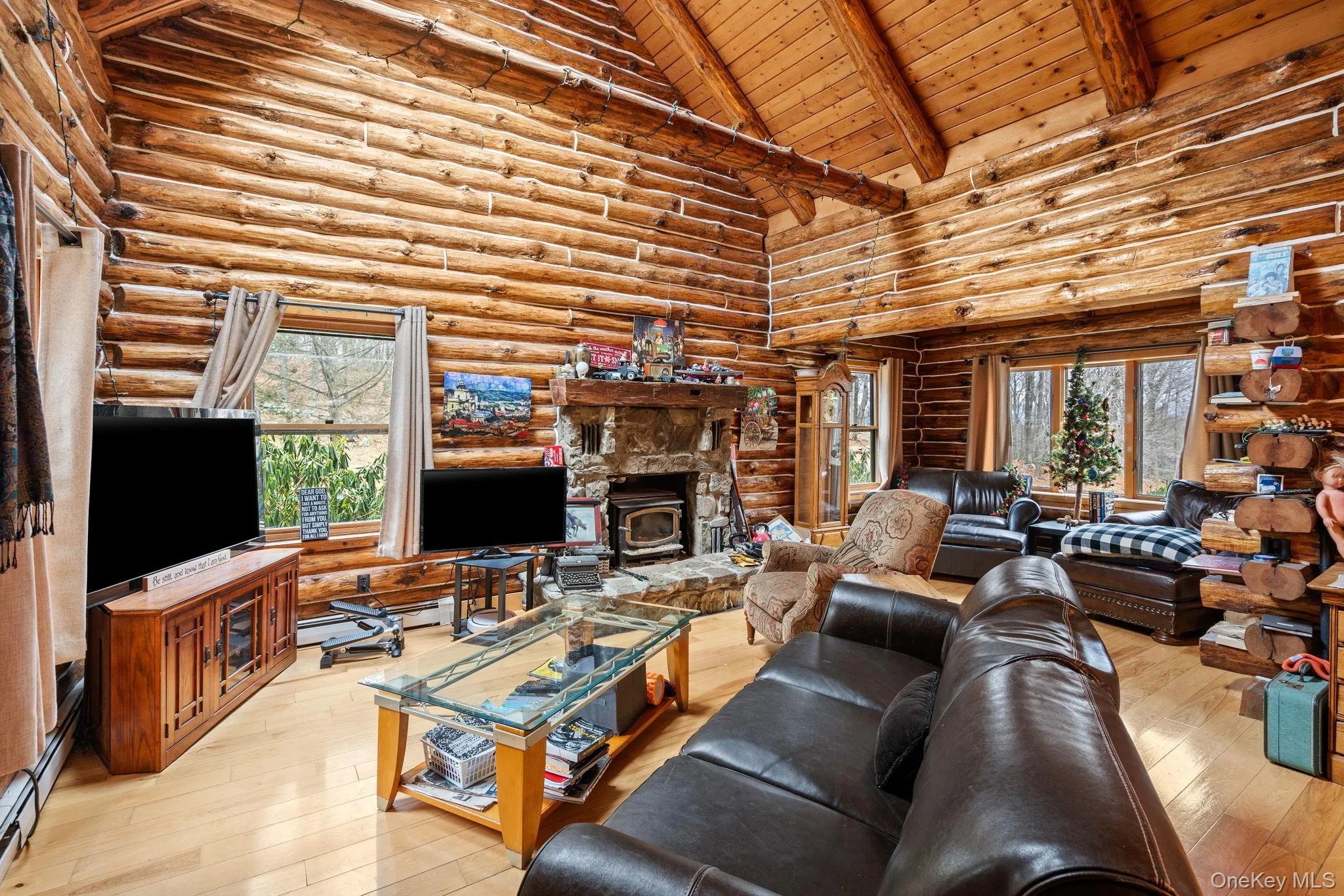 Living area featuring a wood ceiling with exposed beams, log walls, light wood-type flooring, healthy amount of natural light, and high vaulted ceiling Living area featuring a wood ceiling with exposed beams, log walls, light wood-type flooring, healthy amount of natural light, and high vaulted ceiling