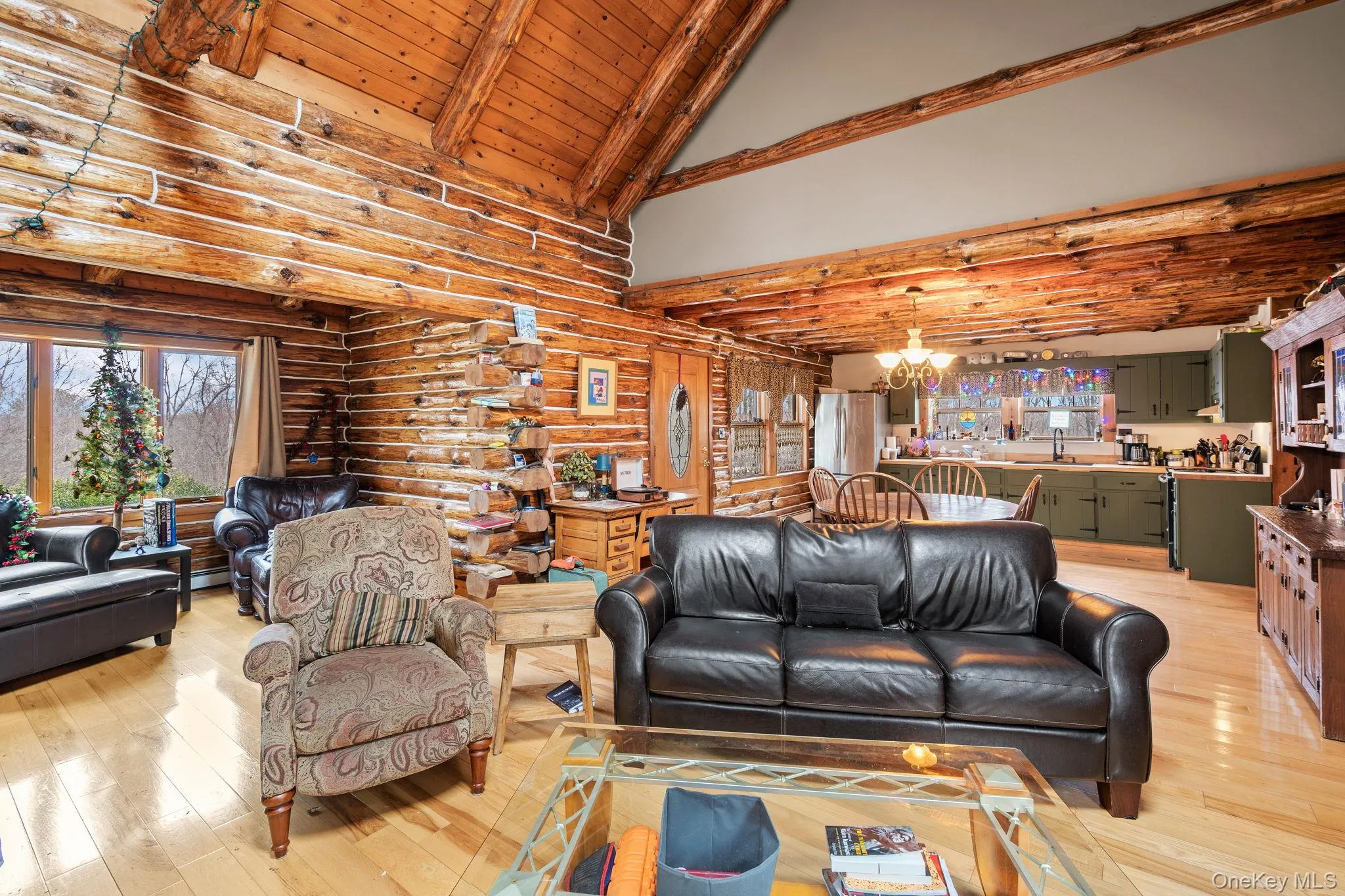 Living room with rustic walls, a chandelier, light wood finished floors, high vaulted ceiling, and a wood ceiling with exposed beams Living room with rustic walls, a chandelier, light wood finished floors, high vaulted ceiling, and a wood ceiling with exposed beams