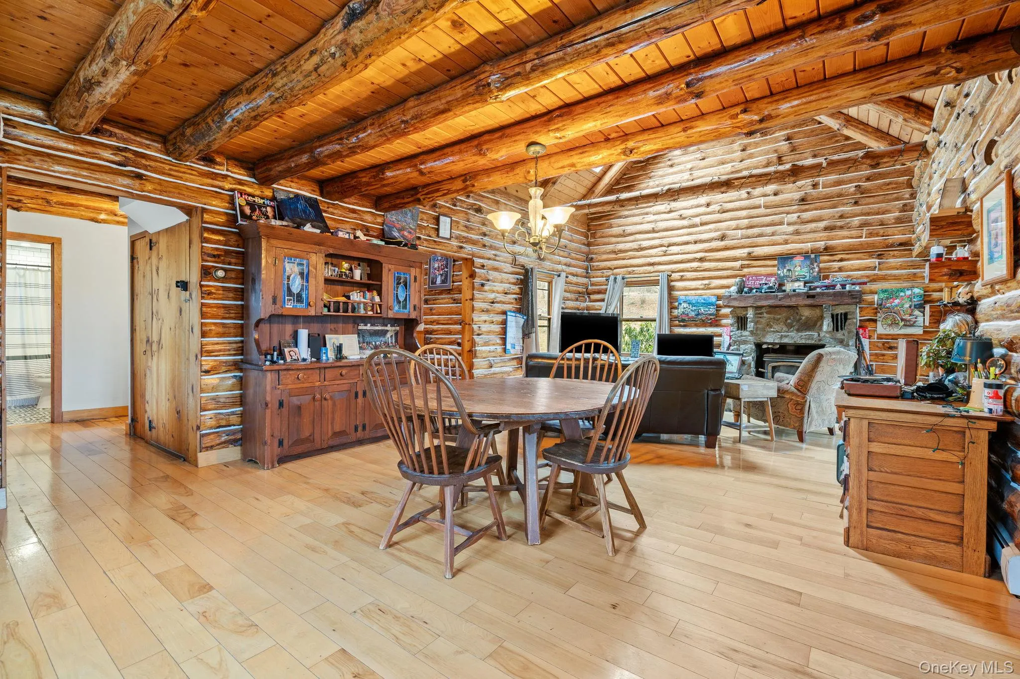 Dining room featuring log walls, a wooden ceiling with exposed beams, a chandelier, light wood finished floors, and plenty of natural light Dining room featuring log walls, a wooden ceiling with exposed beams, a chandelier, light wood finished floors, and plenty of natural light