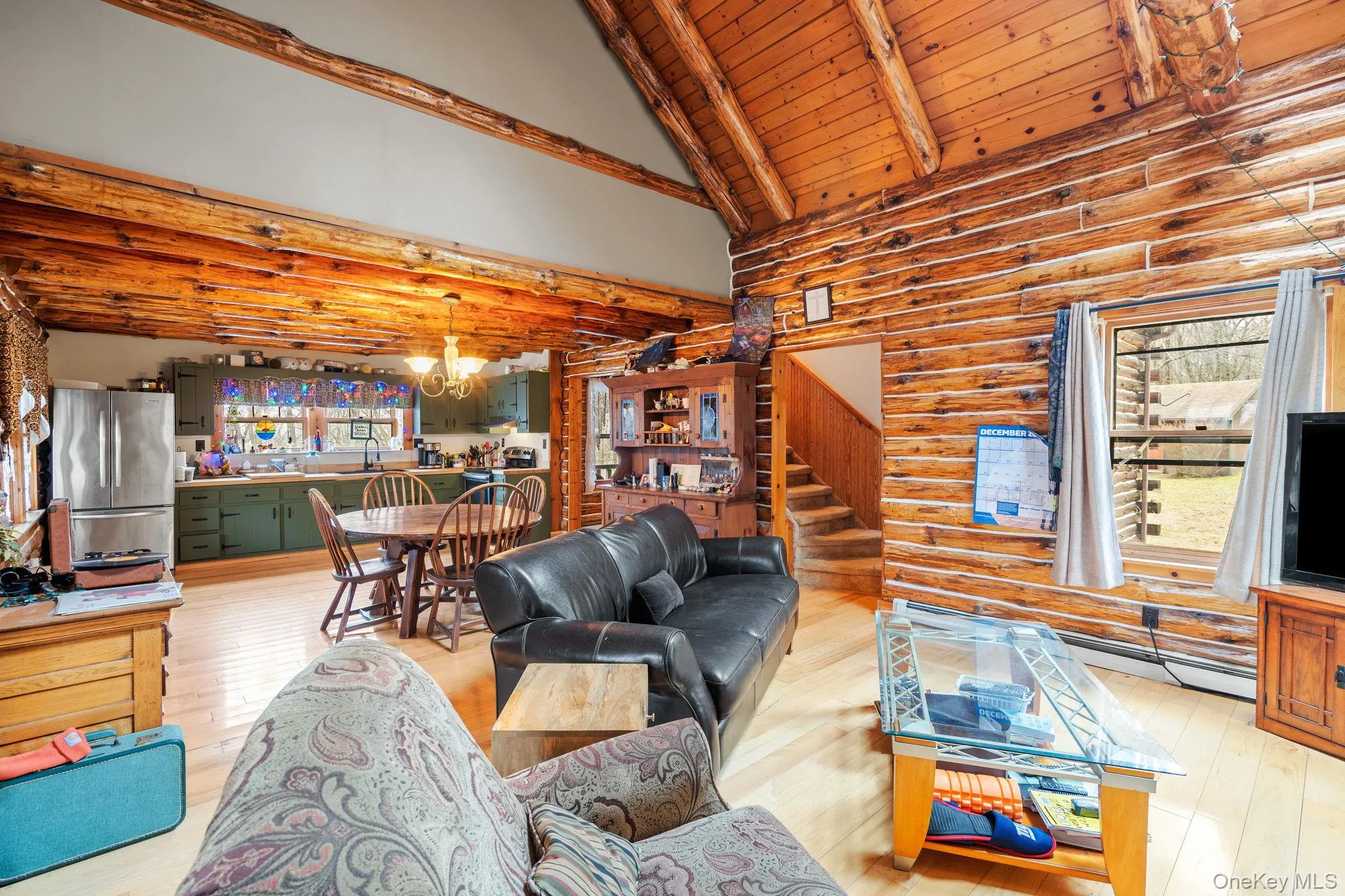 Living room with rustic walls, high vaulted ceiling, a chandelier, a wood ceiling with exposed beams, and light wood-type flooring Living room with rustic walls, high vaulted ceiling, a chandelier, a wood ceiling with exposed beams, and light wood-type flooring