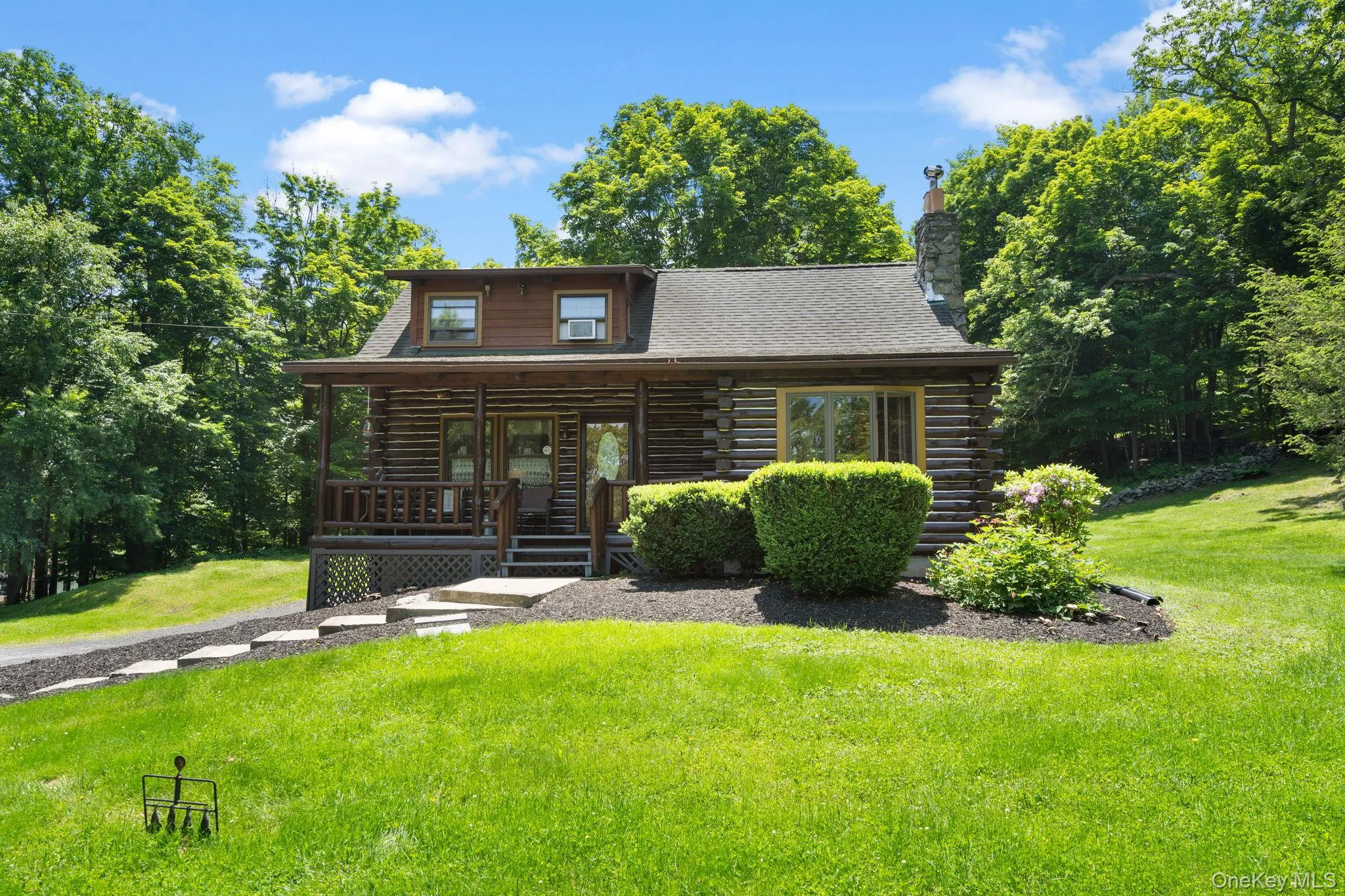 Log home featuring log exterior, a porch, a front lawn, and a chimney Log home featuring log exterior, a porch, a front lawn, and a chimney